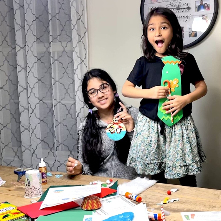 Two young girls sitting at a dining table doing crafts