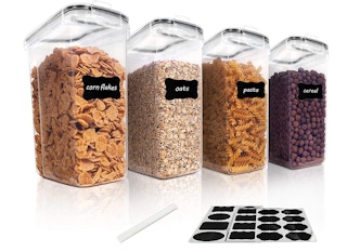 A set of four cereal storage containers near labels and a pen.