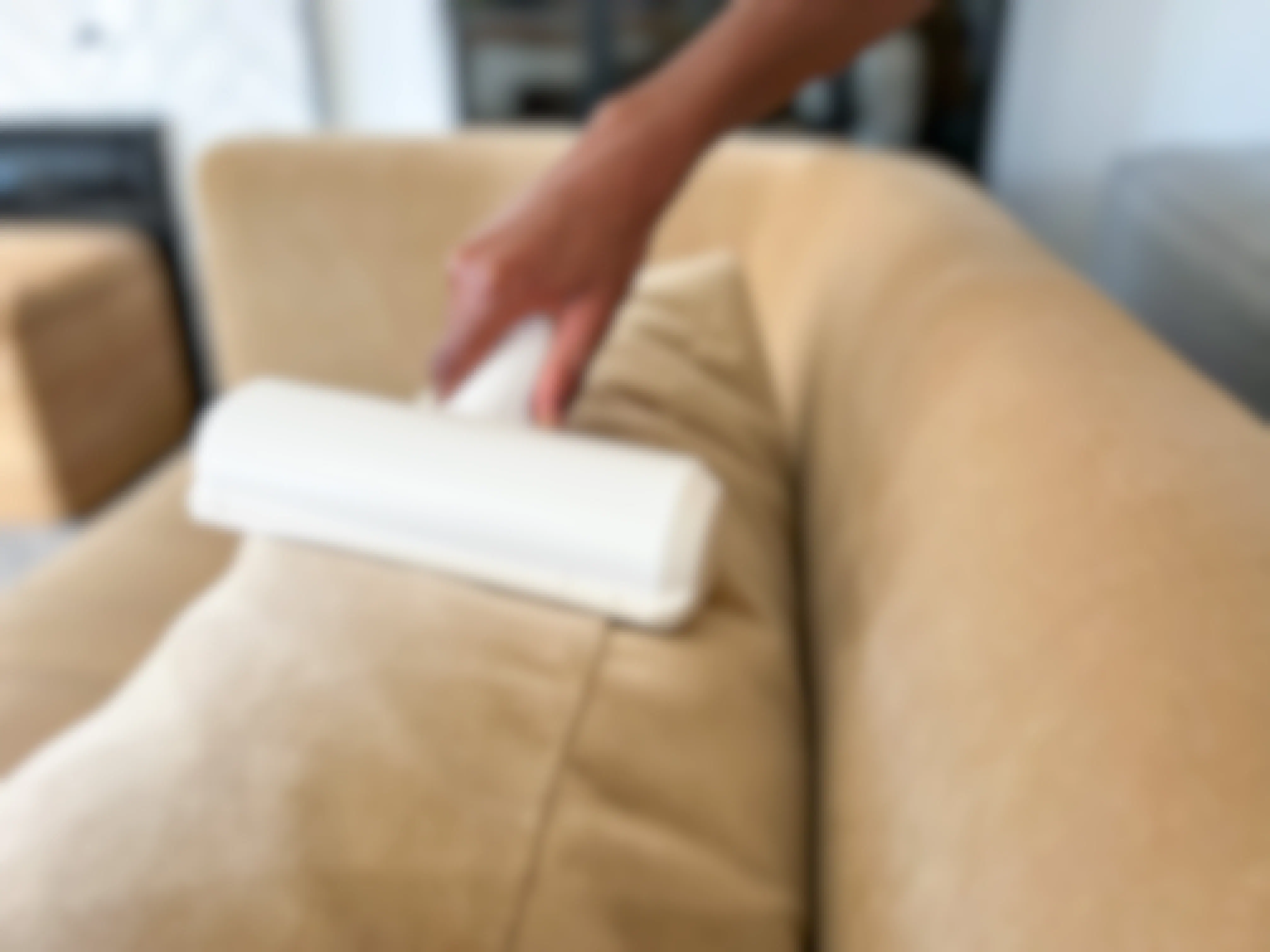 A person using a ChomChom pet hair remover on a couch.