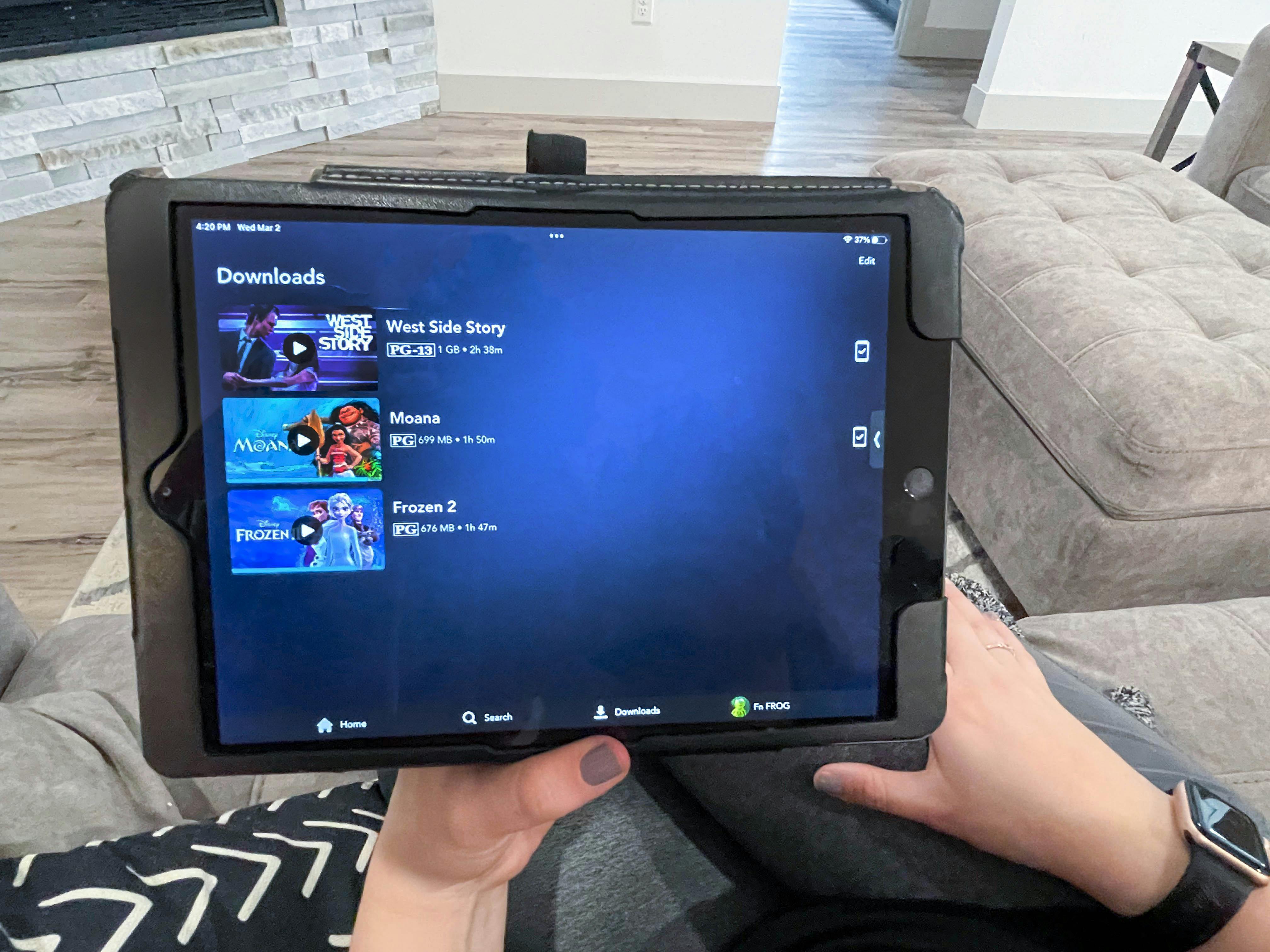woman holding tablet with disney plus downloads on screen