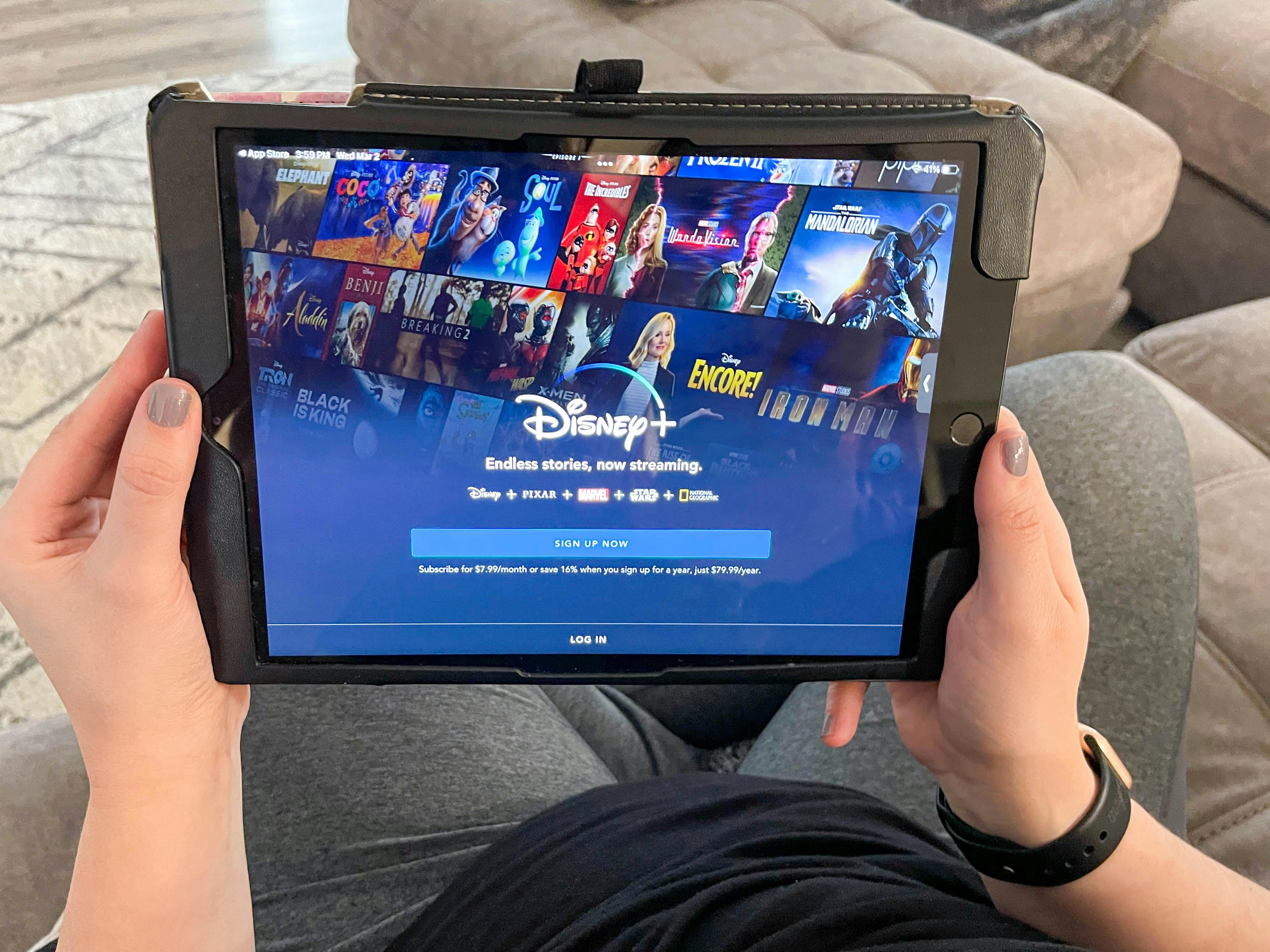 A person holding a tablet displaying the Disney Plus sign up screen.