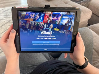 A person holding a tablet displaying the Disney Plus sign up screen.