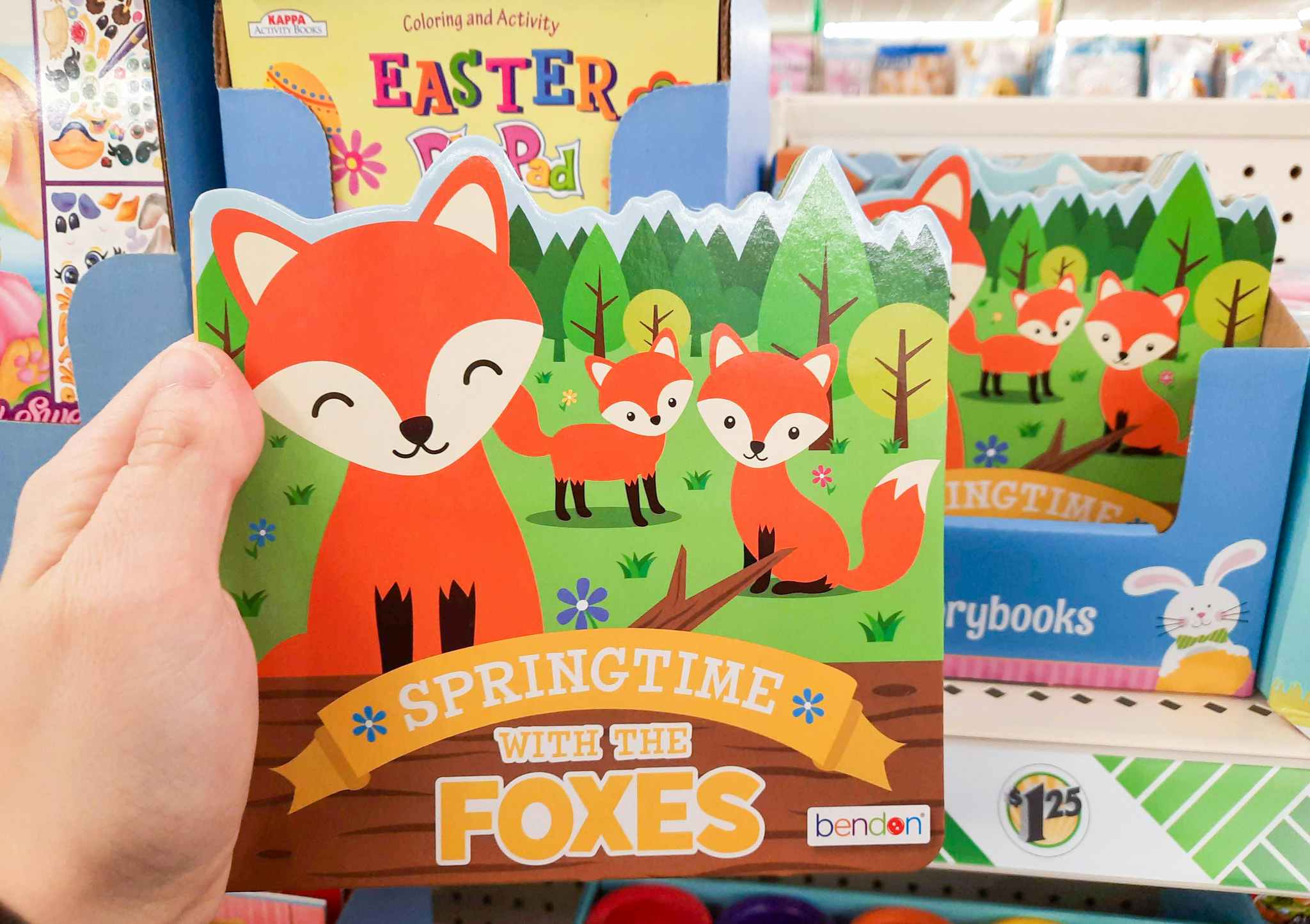 A person's hand holding up a Spring Time With The Foxes book at Dollar Tree