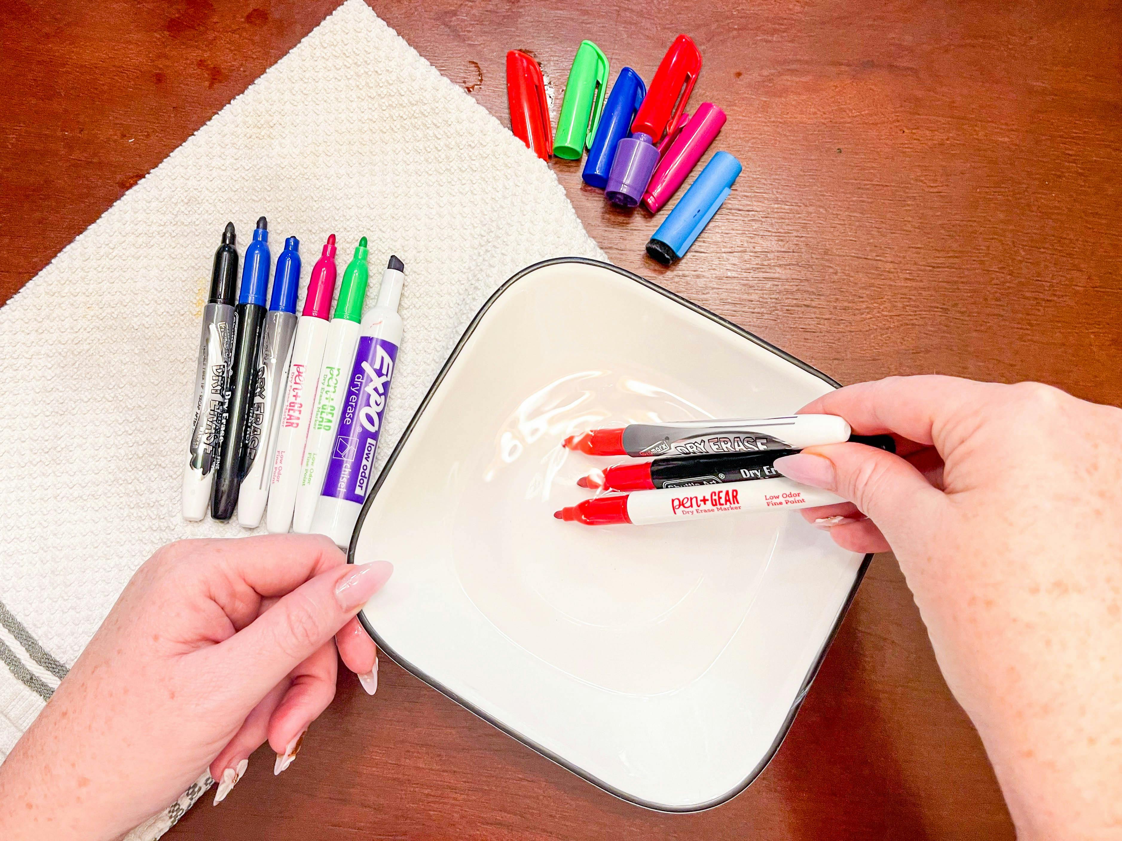 dipping dry erase markers in a bowl of hot water