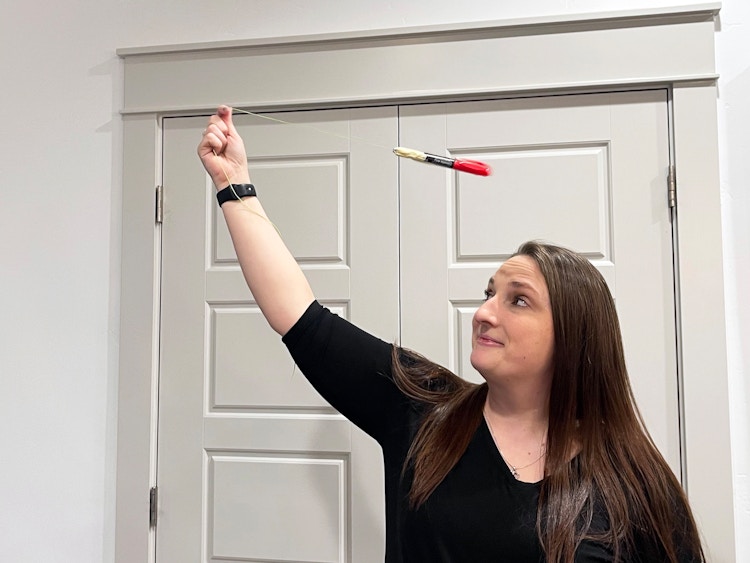 woman swinging a marker on a string over her head