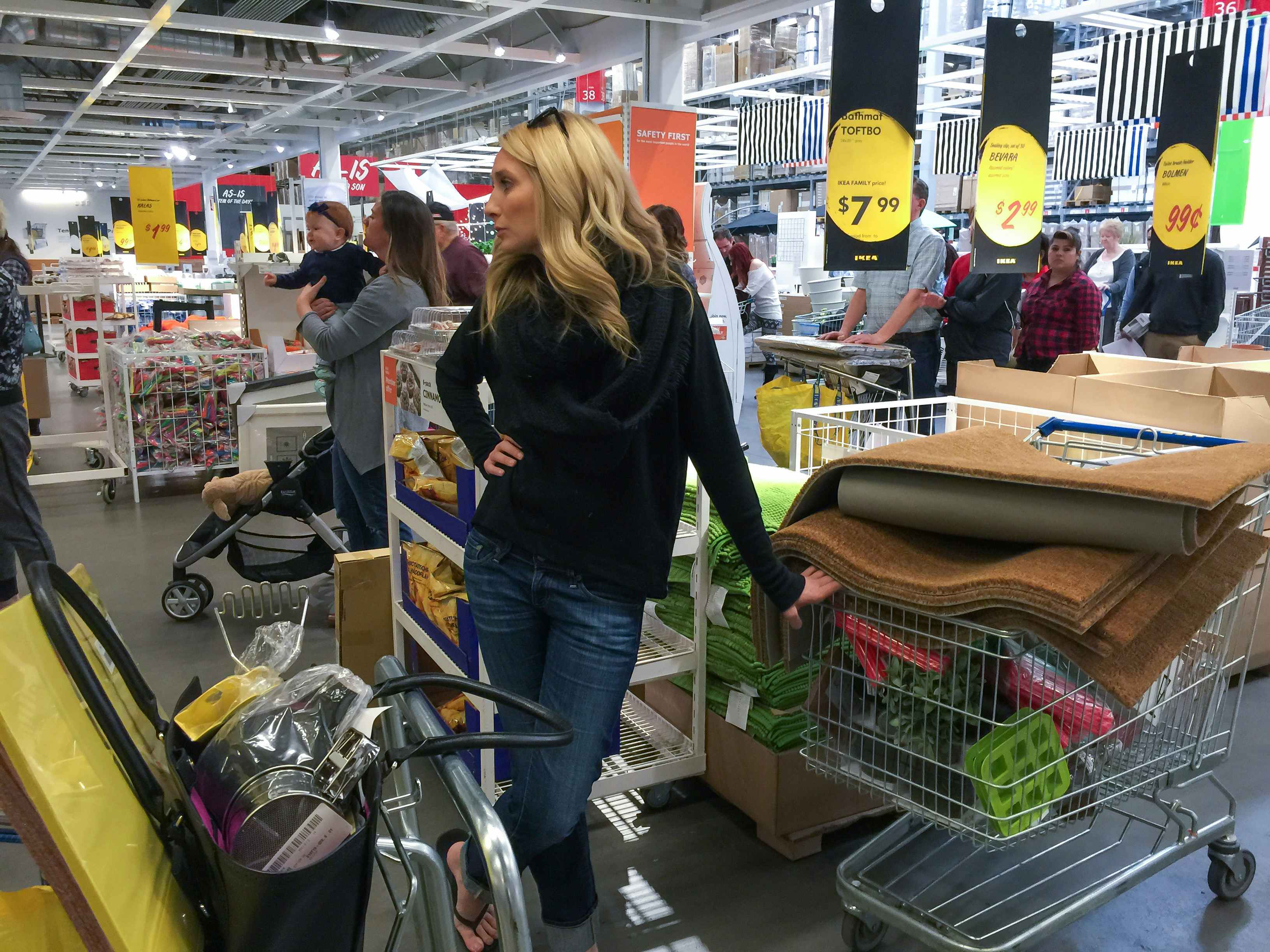 a woman leaning on her cart full of items at the IKEA store surrounded by other shoppers