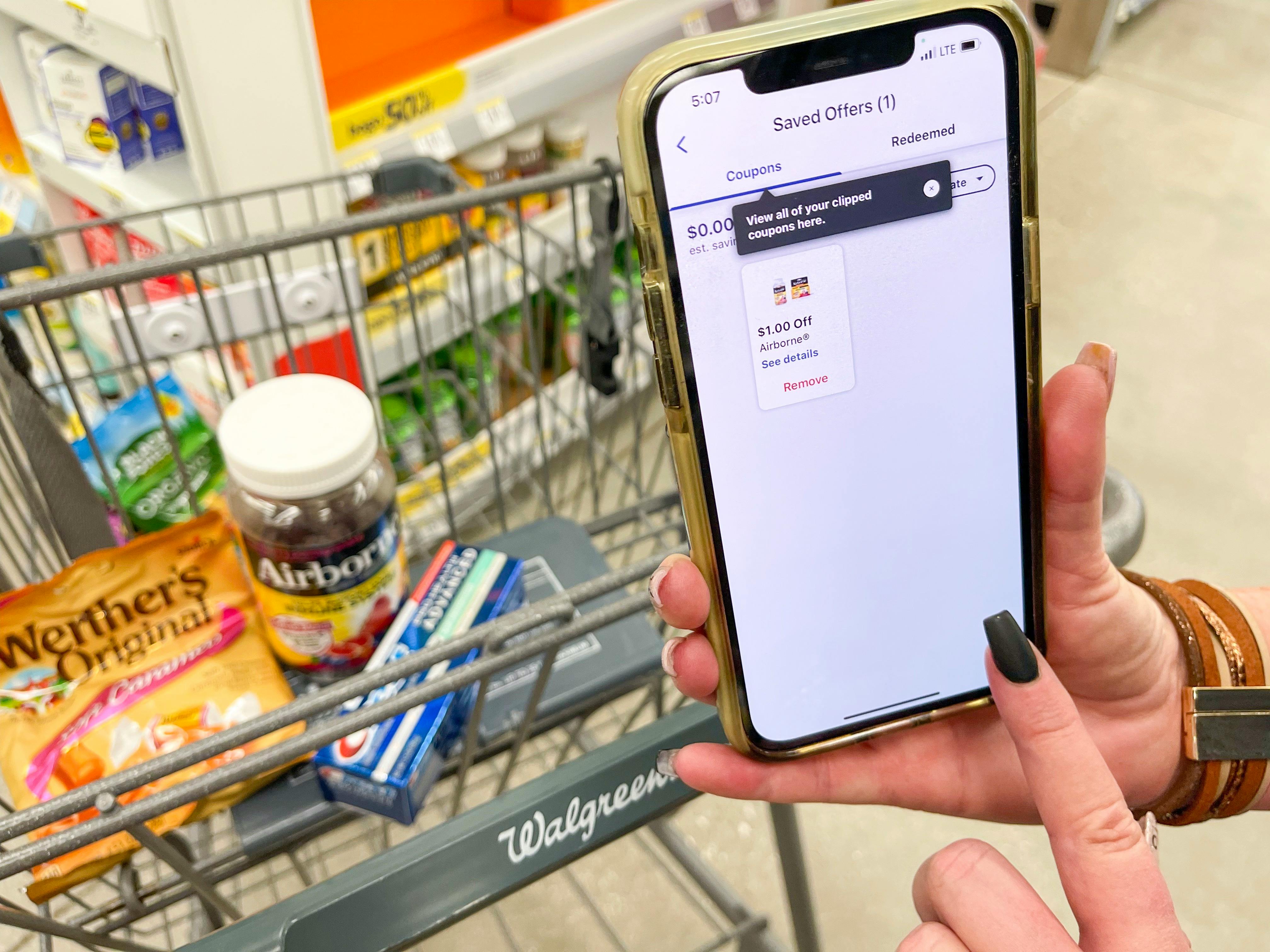someone holding phone with walgreens app next to cart
