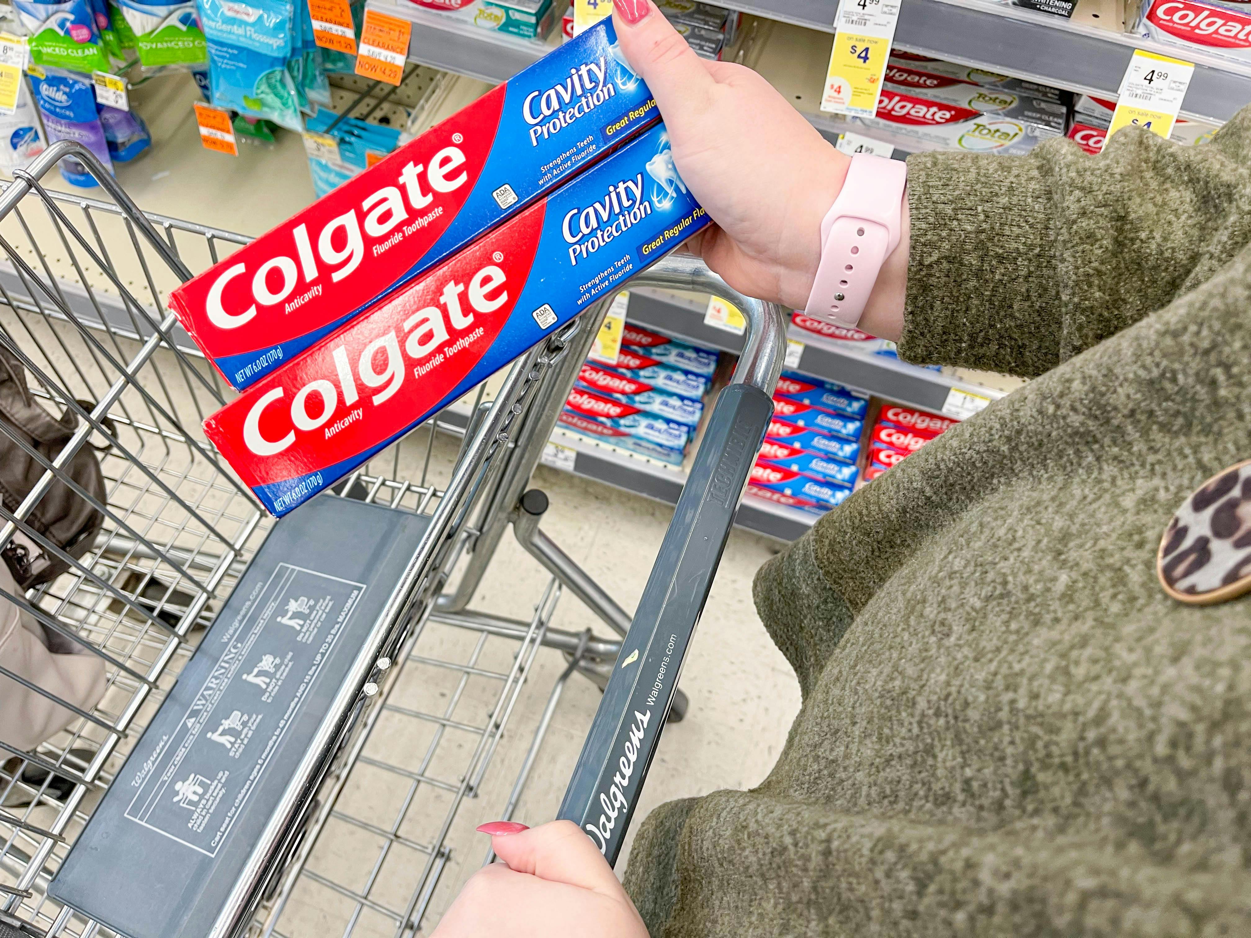 holding colgate toothpaste and putting in walgreens cart