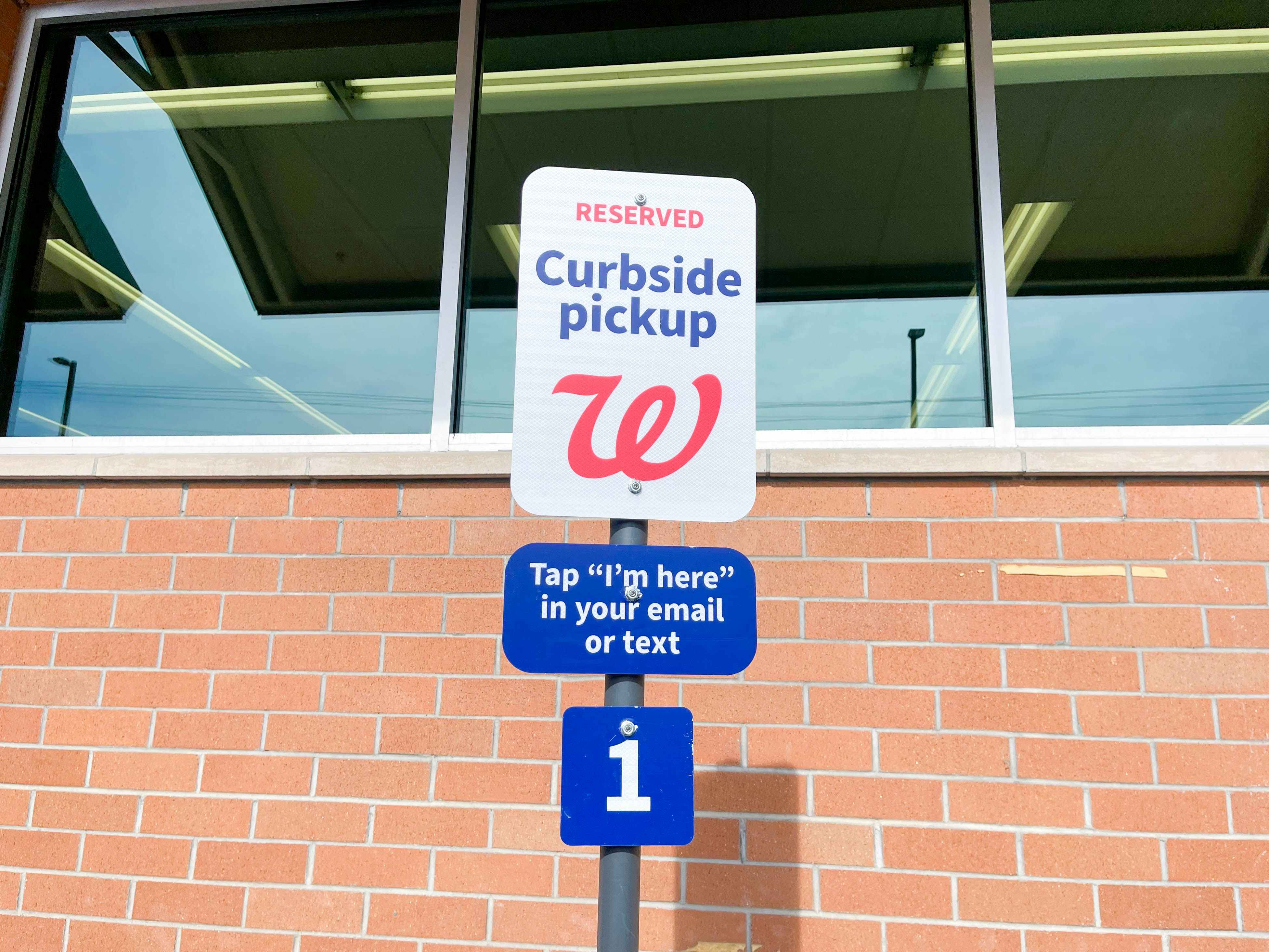 A curbside pickup sign outside of Walgreens that reads, "Reserved Curbside Pickup. Tap 'I'm here' in your email or text