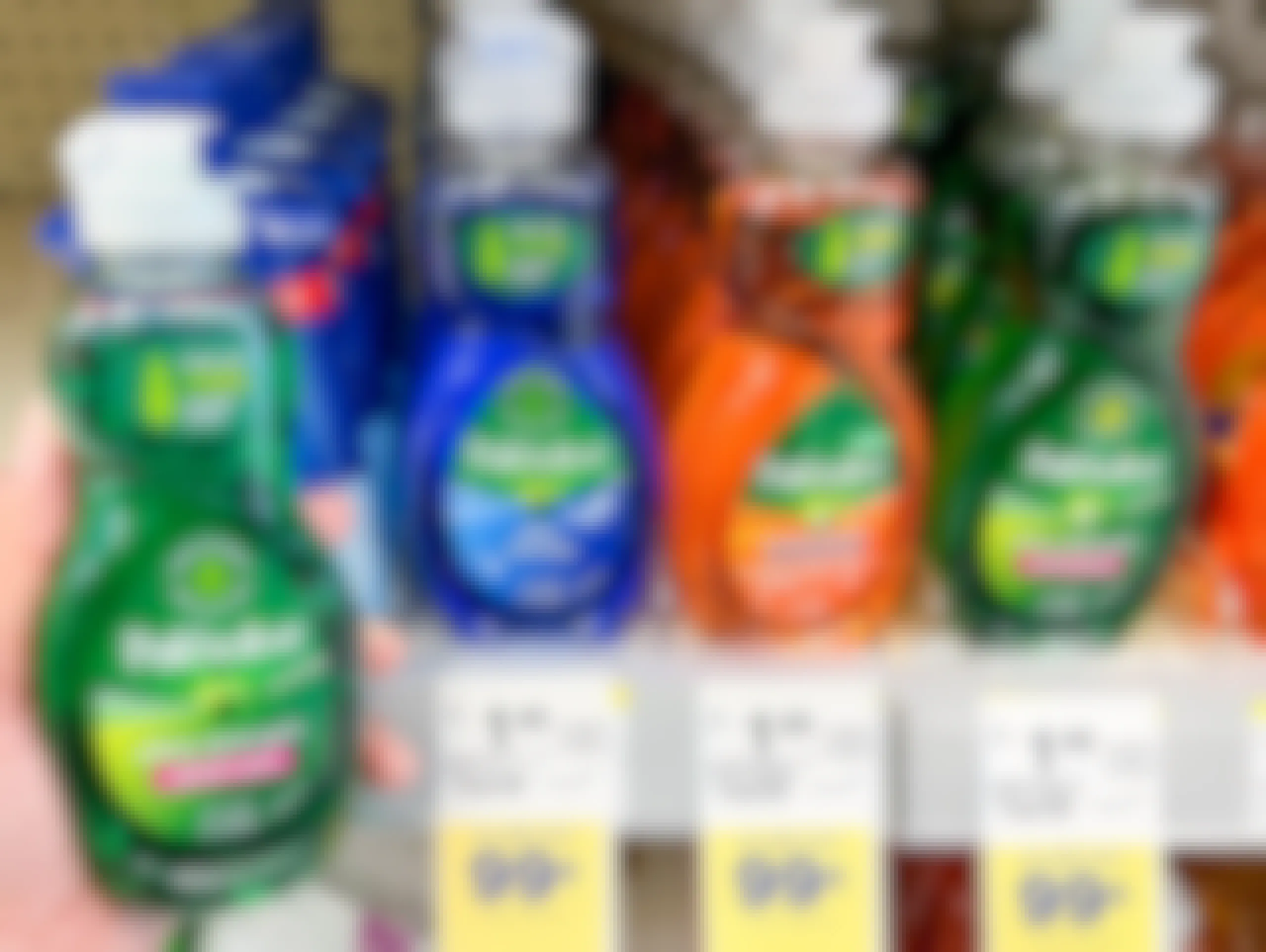 A person's hand holding a bottle of Palmolive Ultra Strength liquid dish soap next to a shelf of different variations of Palmolive liquid dish soap at Walgreens.