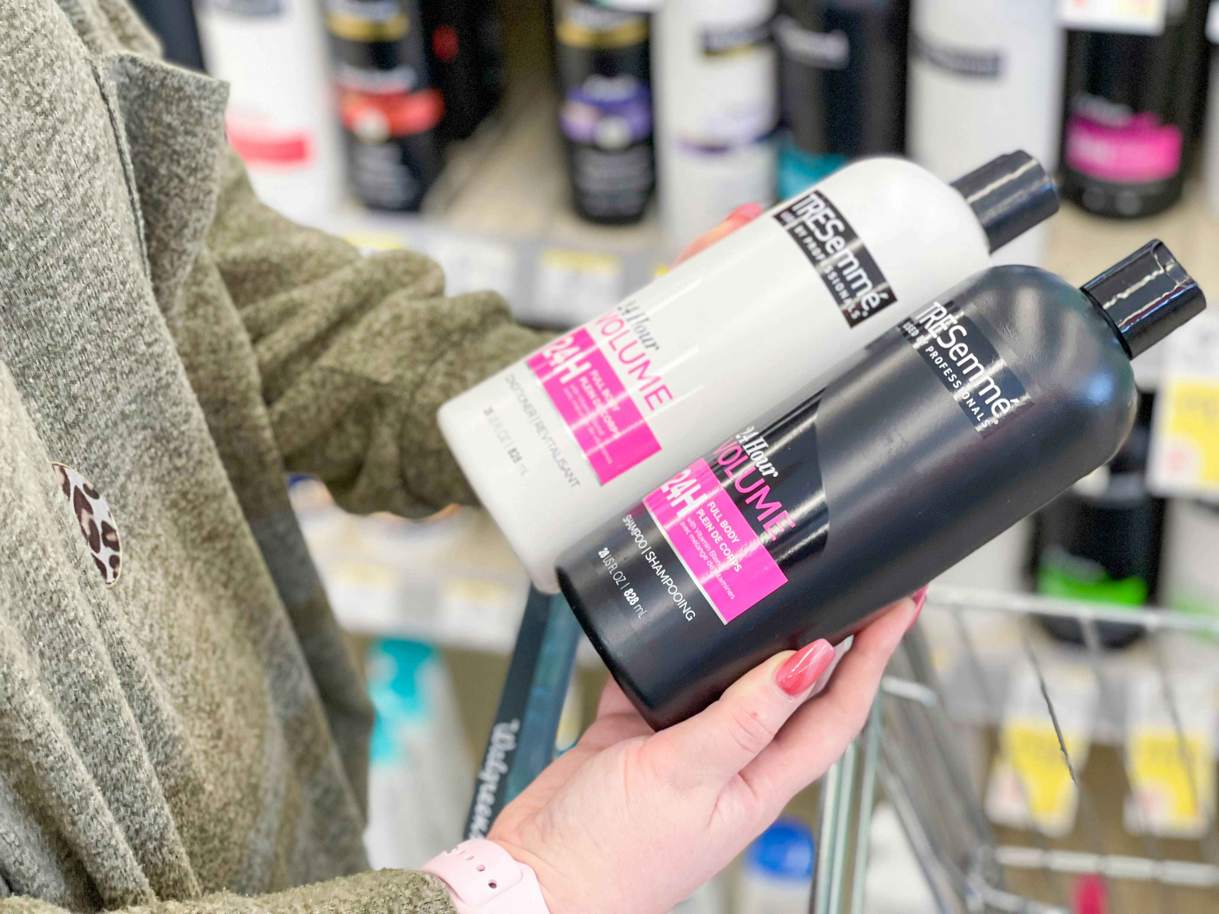 A person holding bottles of TRESemme shampoo and conditioner in the hair care aisle of Walgreens.