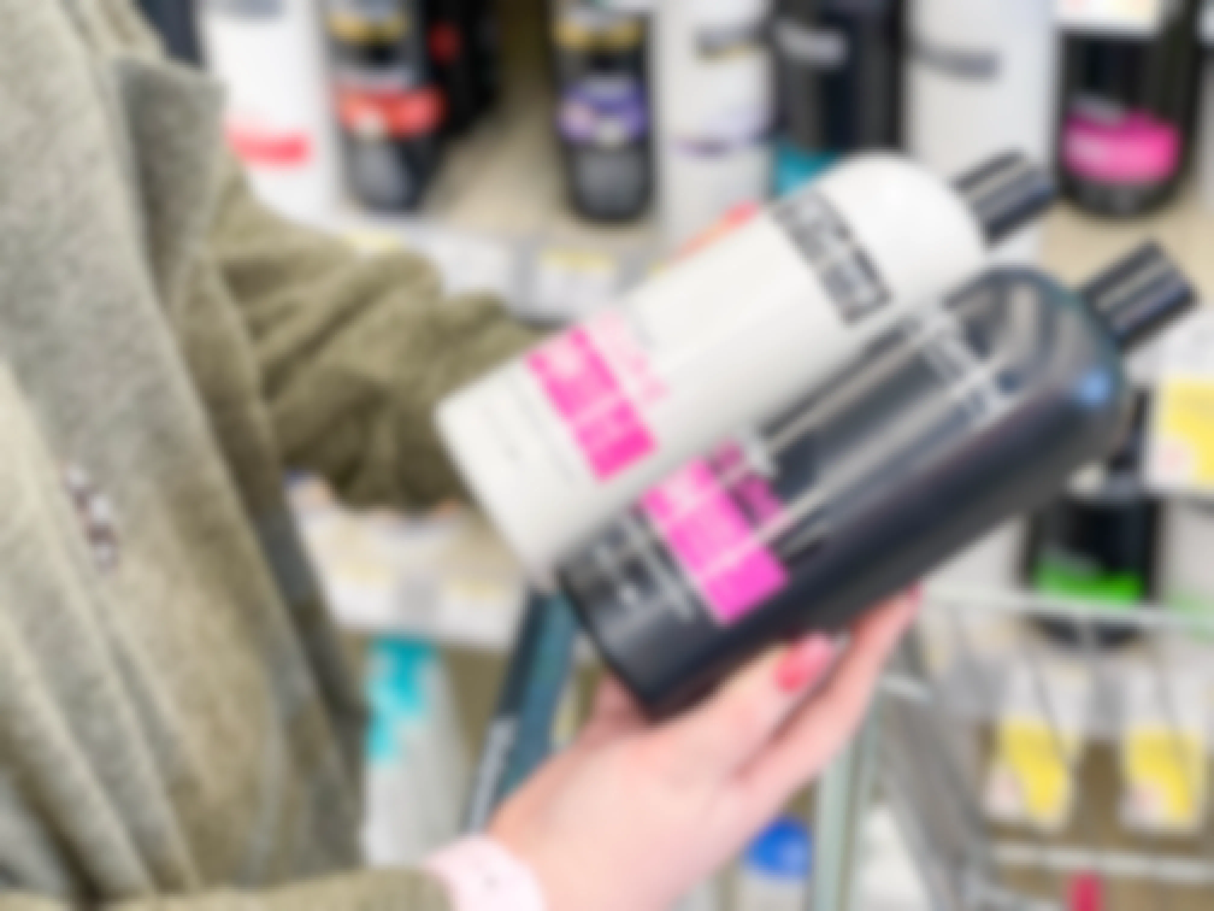 A person holding bottles of TRESemme shampoo and conditioner in the hair care aisle of Walgreens.