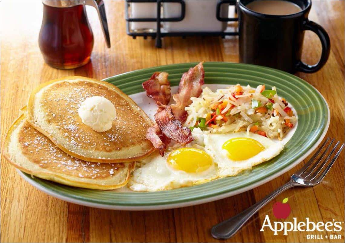 Pancakes, bacon, two eggs suny side up, and potato hash on a plate at Applebee's