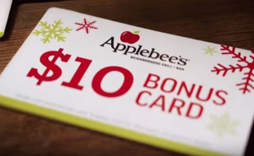 A close-up of a holiday-themed Applebee's $10 Bonus Card sitting on a table.
