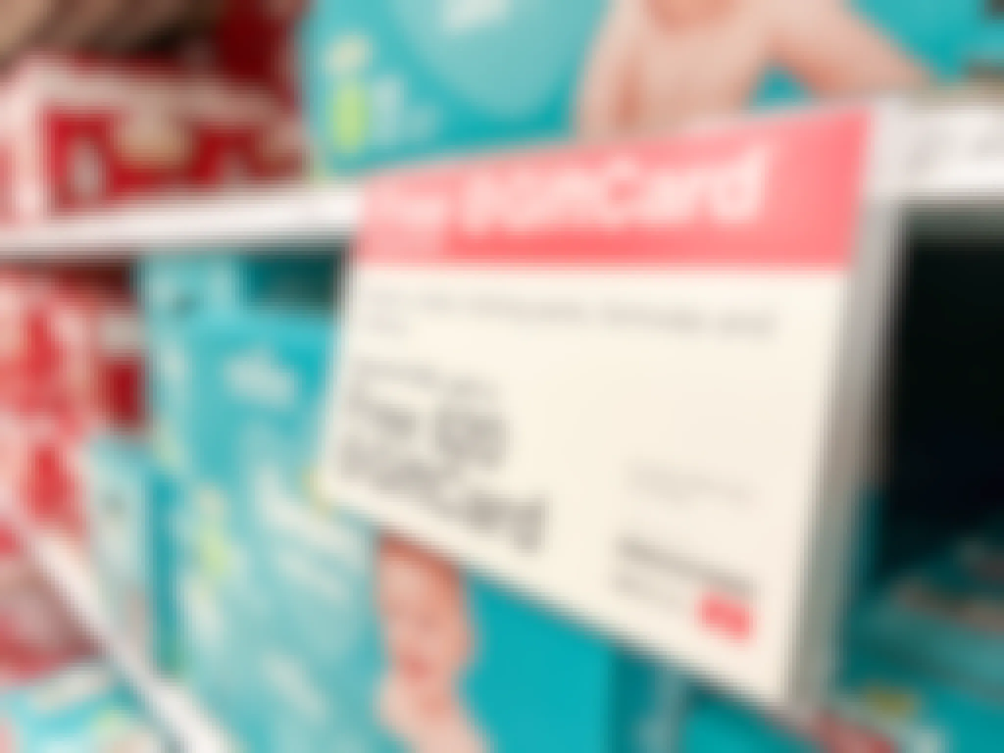 A shelf filled with pampers baby diapers with a sign that says Free Target Gift Card with $100 purchases of diapers, wipes, training pants, formulas, and toiletries