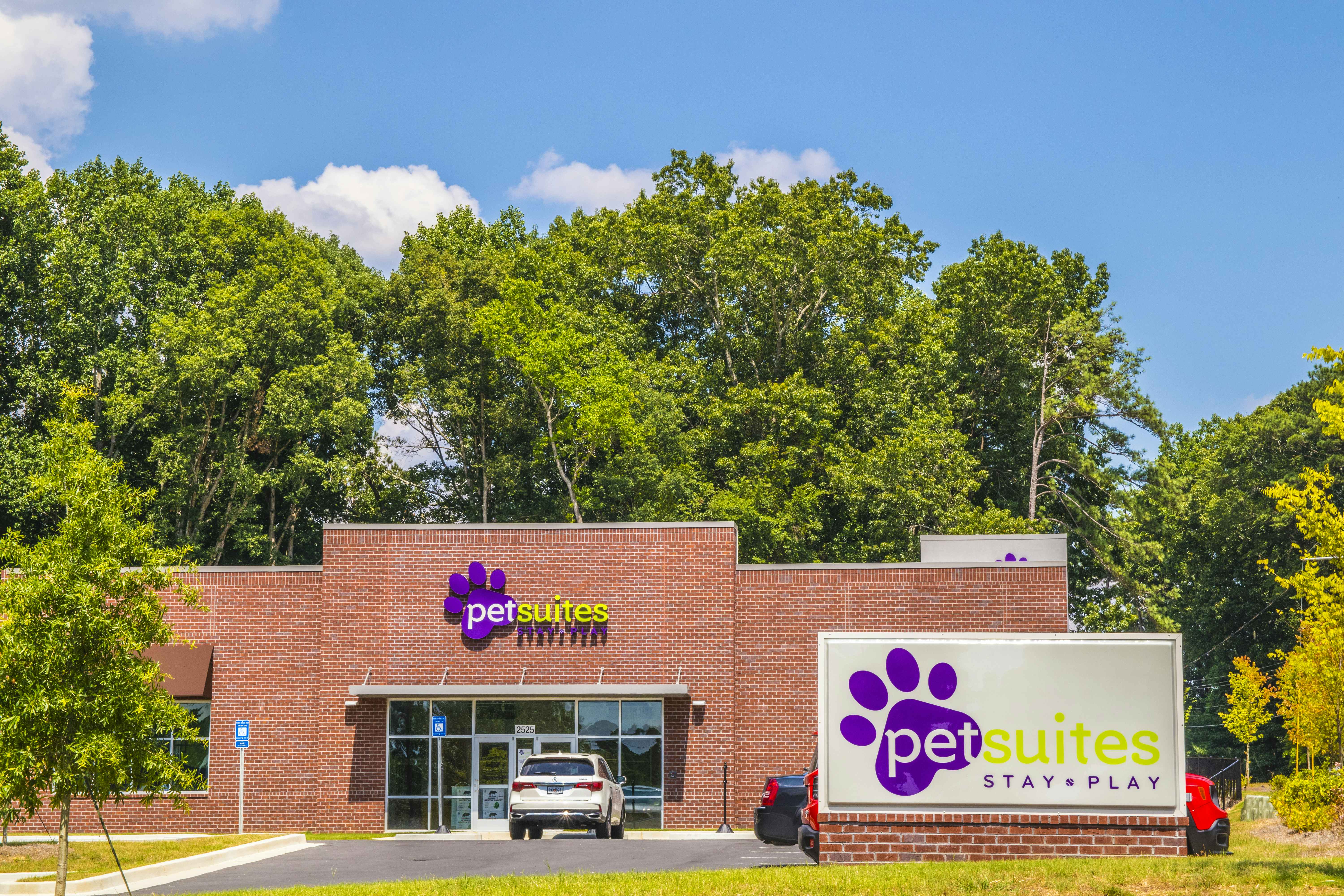 front entrance view of a PetSuites pet boarding facility with road sign