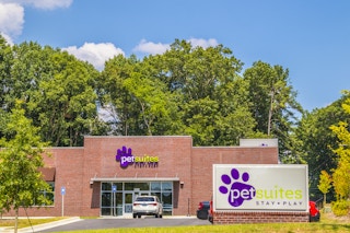 front entrance view of a PetSuites pet boarding facility with road sign