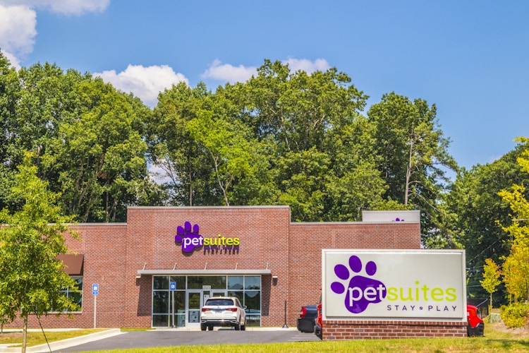 front entrance view of a PetSuites pet boarding facility with road sign