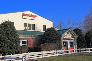 front entrance of a Best Friends pet boarding and care facility with a white fence around front yard