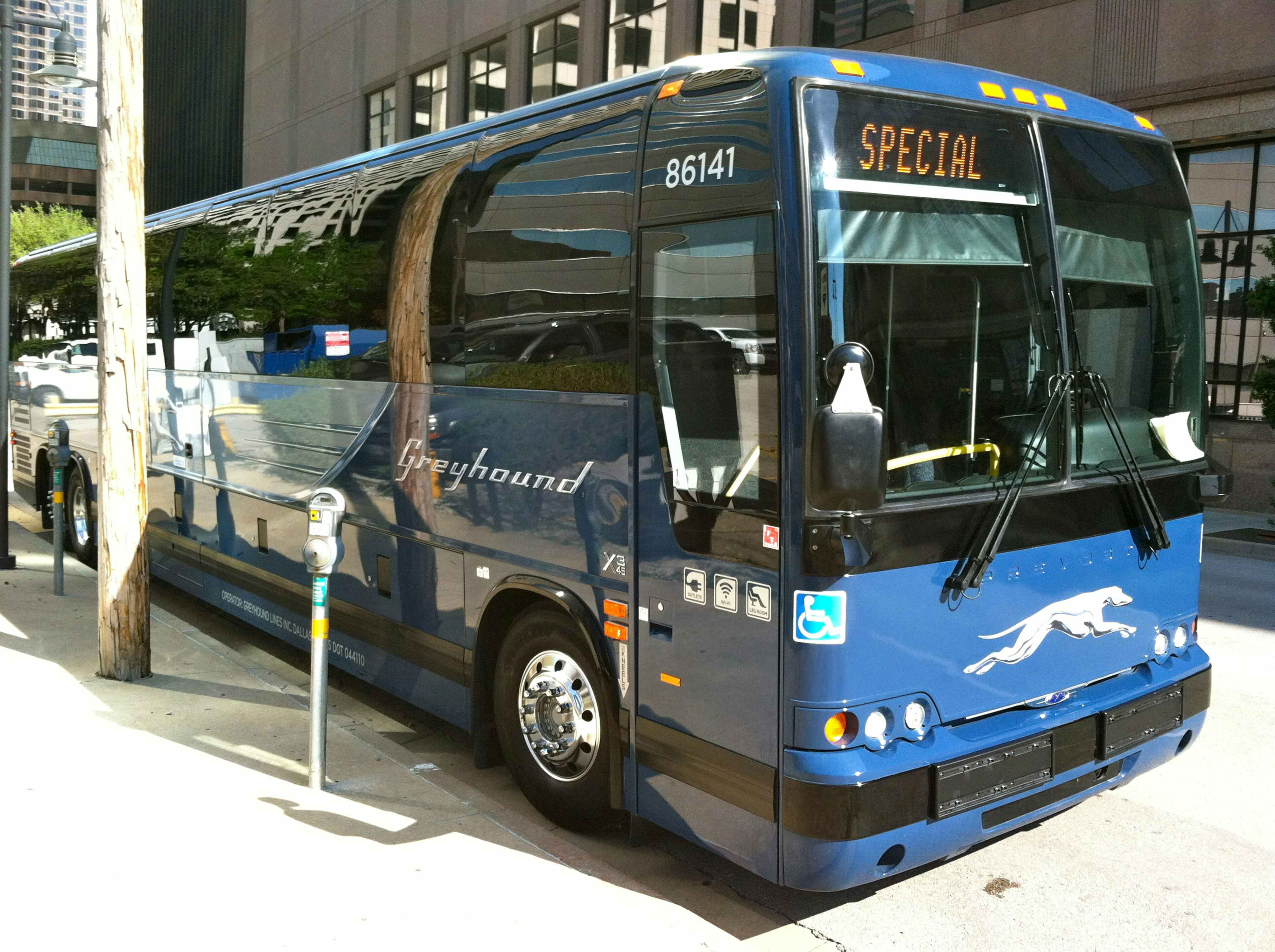 A greyhound bus parked curbside in a city or metropolitan area