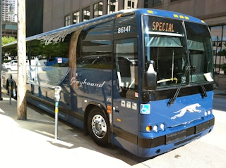 A greyhound bus parked curbside in a city or metropolitan area