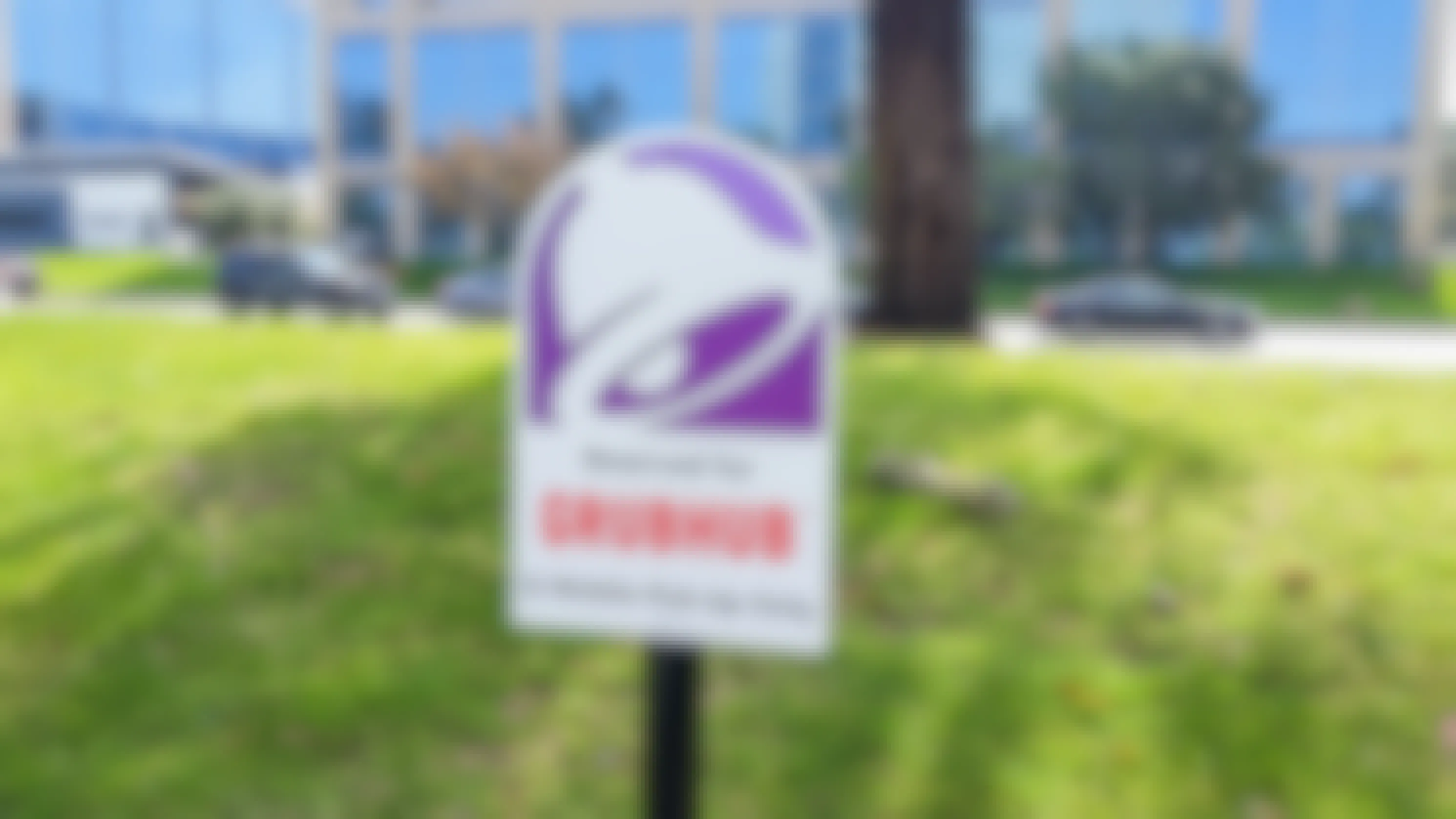 - A Taco Bell sign positioned at a parking space. The sign has the Taco Bell logo and reads 
