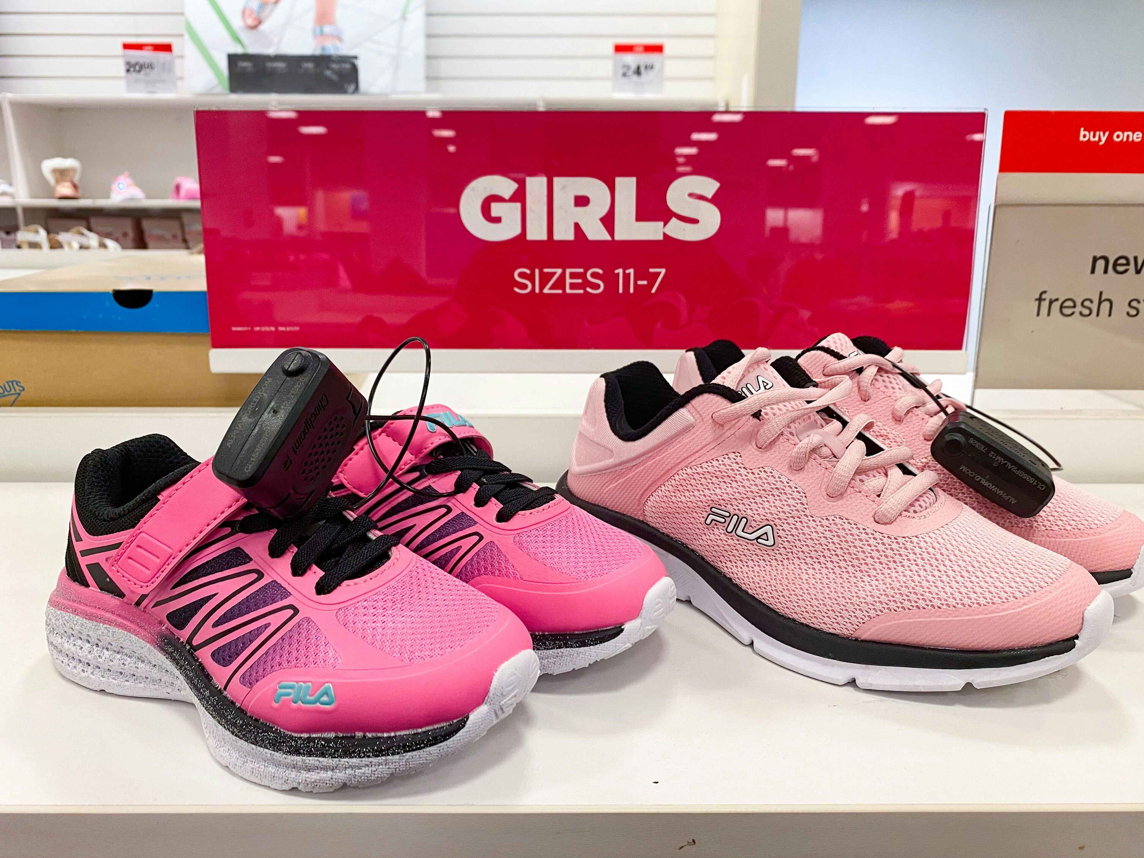 Two pairs of pink Fila running shoes next to a sign that says "Girls Size 11-7