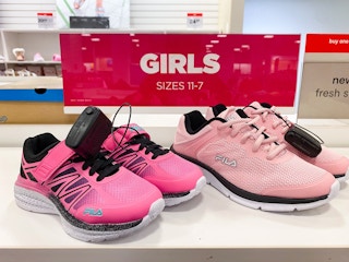 Two pairs of pink Fila running shoes next to a sign that says "Girls Size 11-7