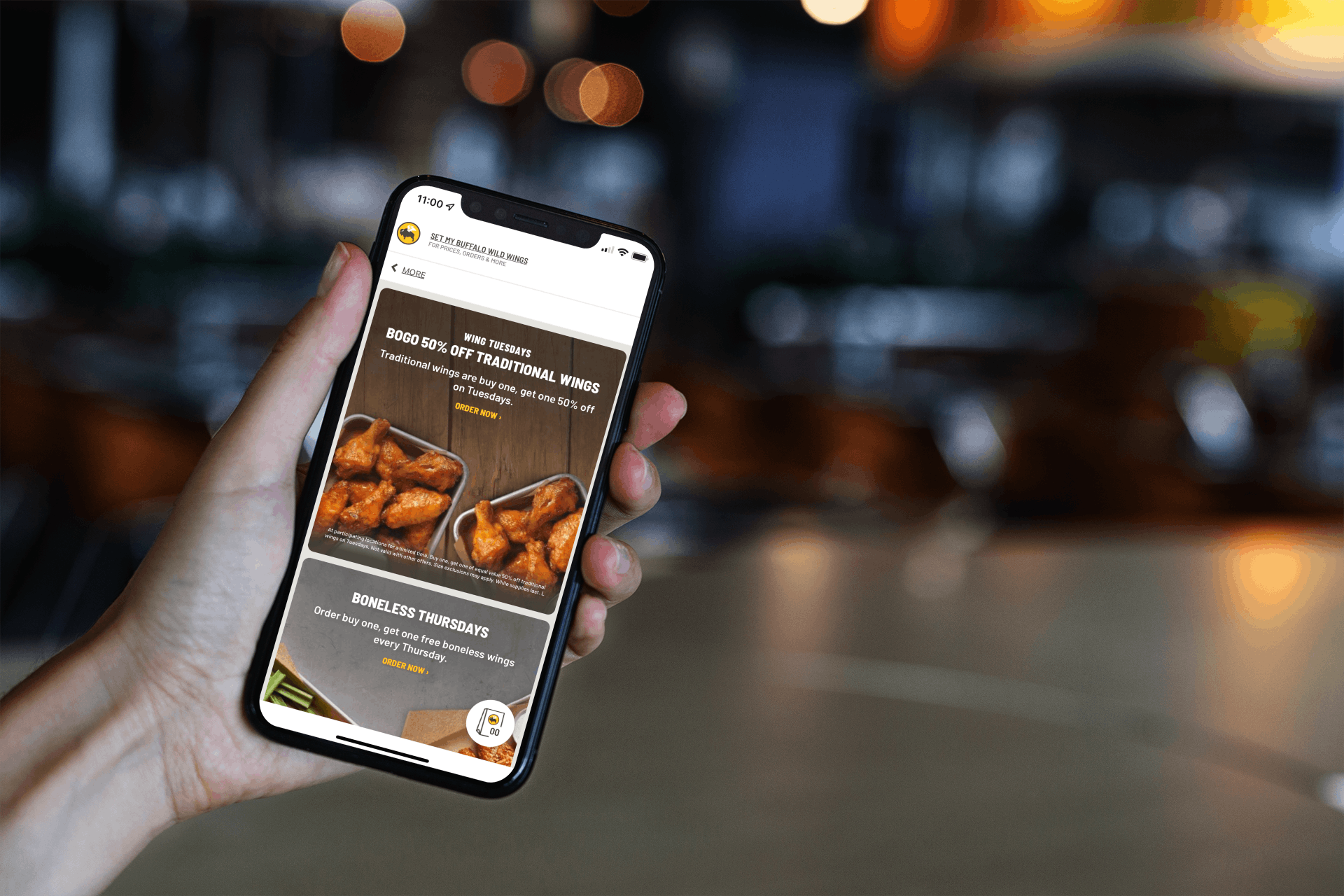 A person holding their iPhone up showing the Buffalo Wild Wings app open to the promotional page.