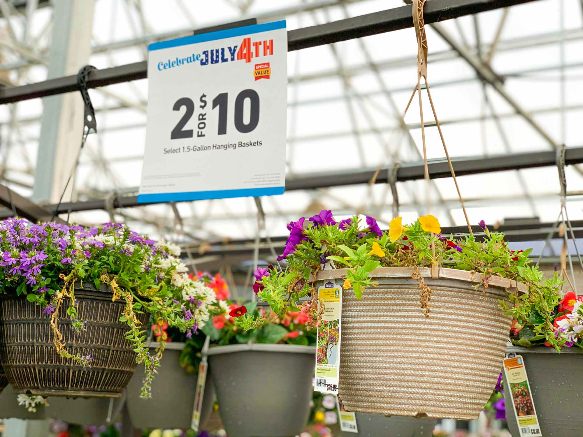 Hanging flower baskets on display at Lowe's with a sign that says 2 for $10