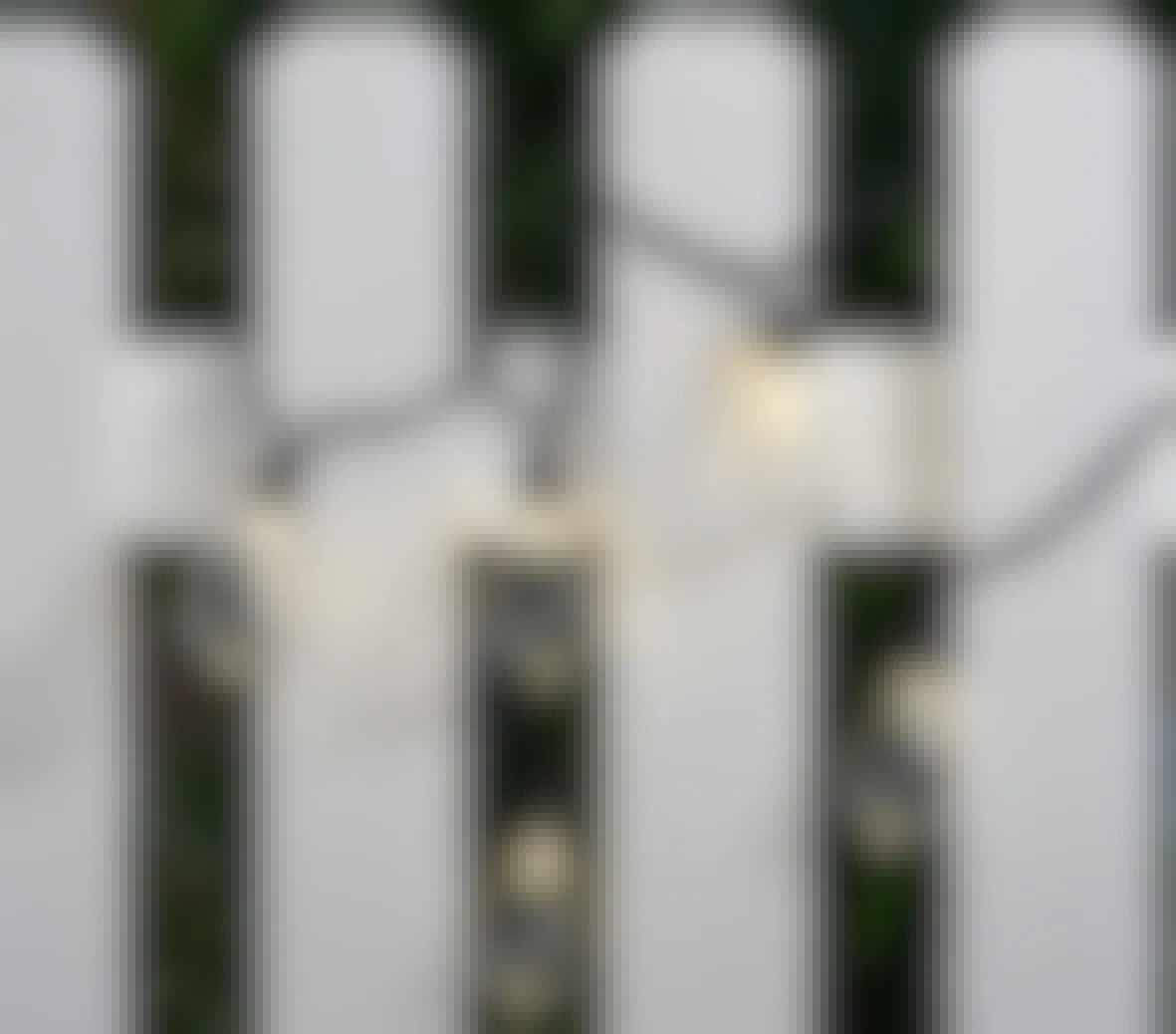 screenshot of Walmart's mainstays outdoor string lights; lights are shown wrapped around white fencing