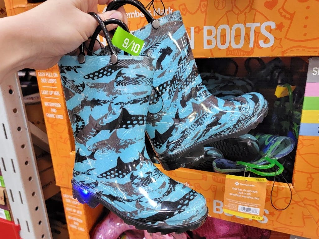 Someone holding up a pair of rain boots in a Sam's Club store