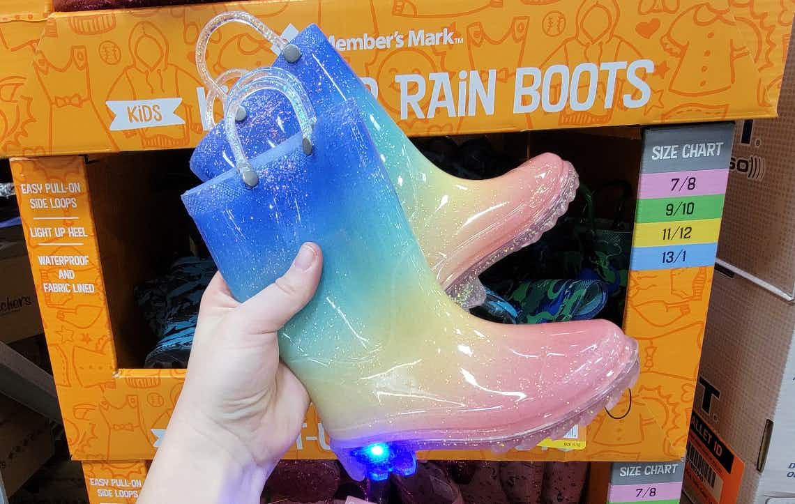 hand holding a pair of rainbow ombre rain boots for kids