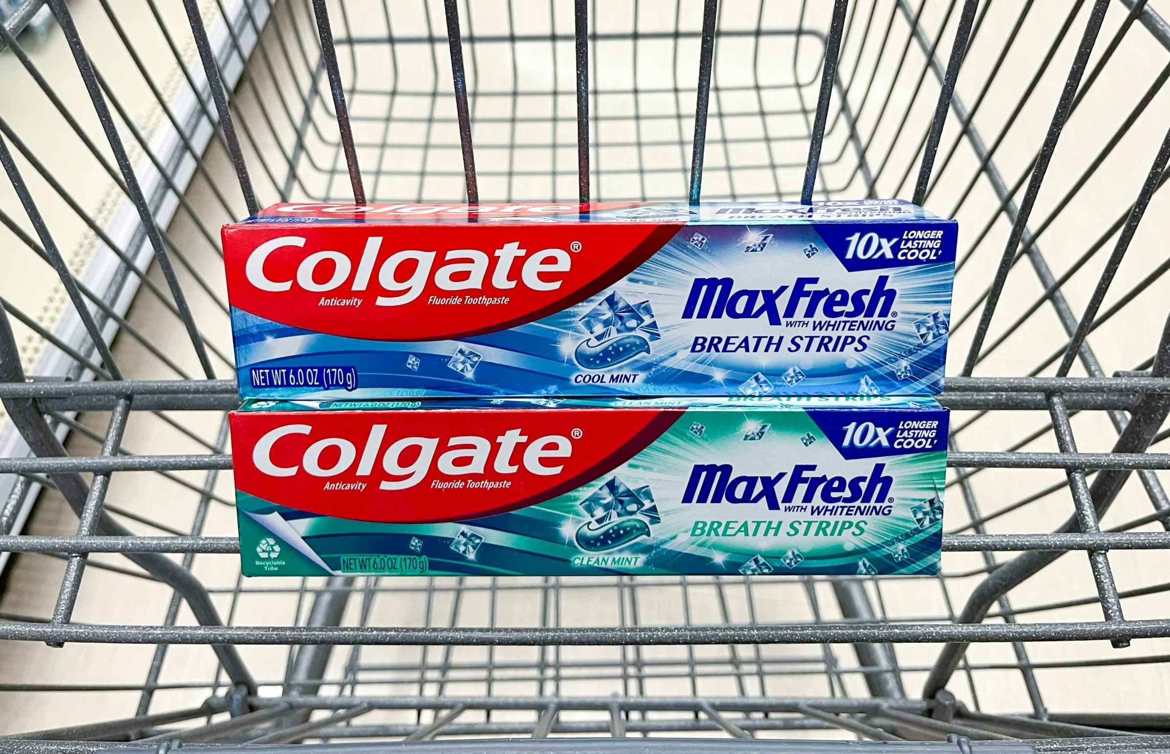 Two boxes of Colgate MaxFresh toothpaste stacked in a Walgreens shopping cart basket.