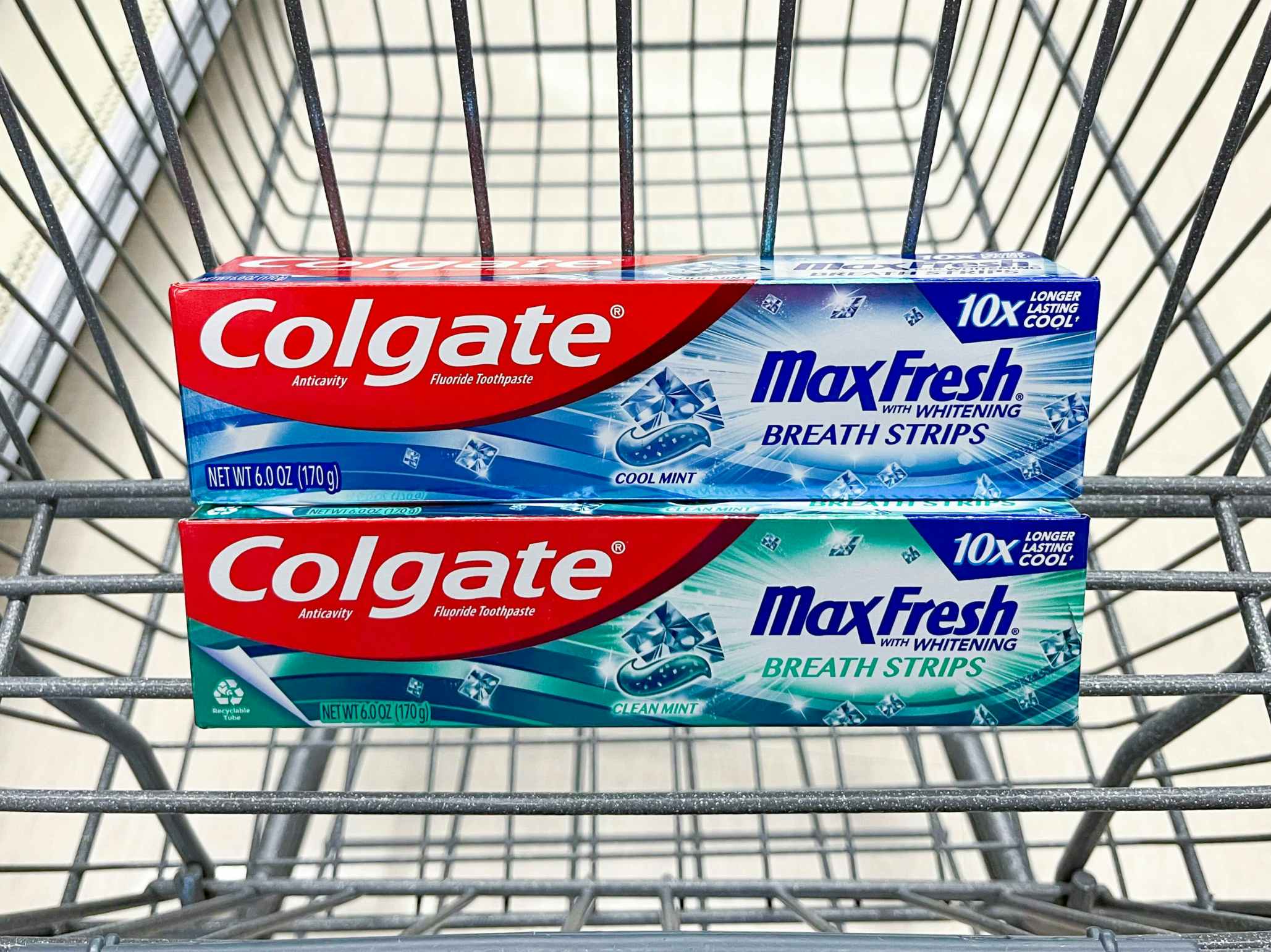 Two boxes of Colgate MaxFresh toothpaste stacked in a Walgreens shopping cart basket.