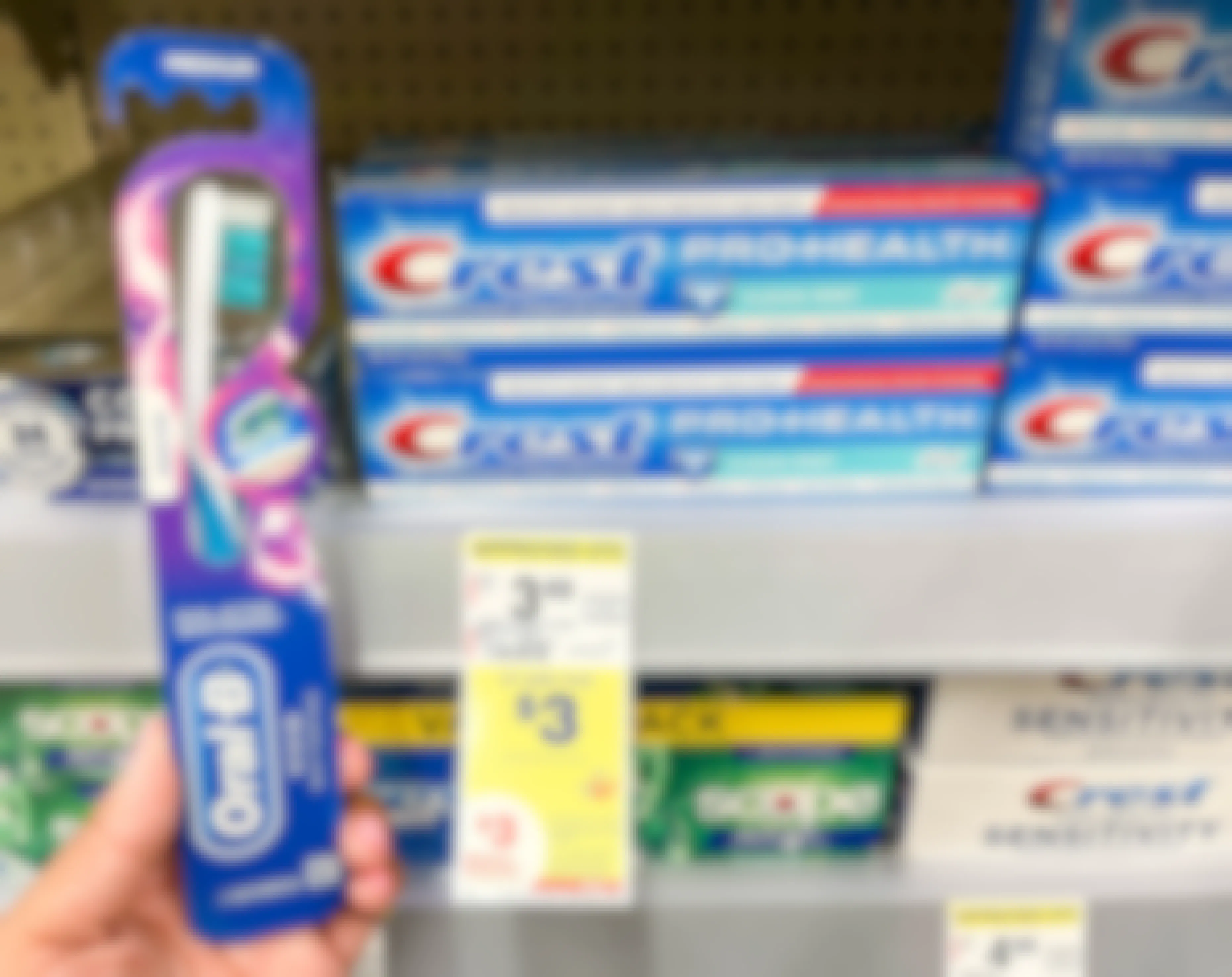 A person holding an oral-b toothbrush next to a shelf holding crest pro-health toothpaste