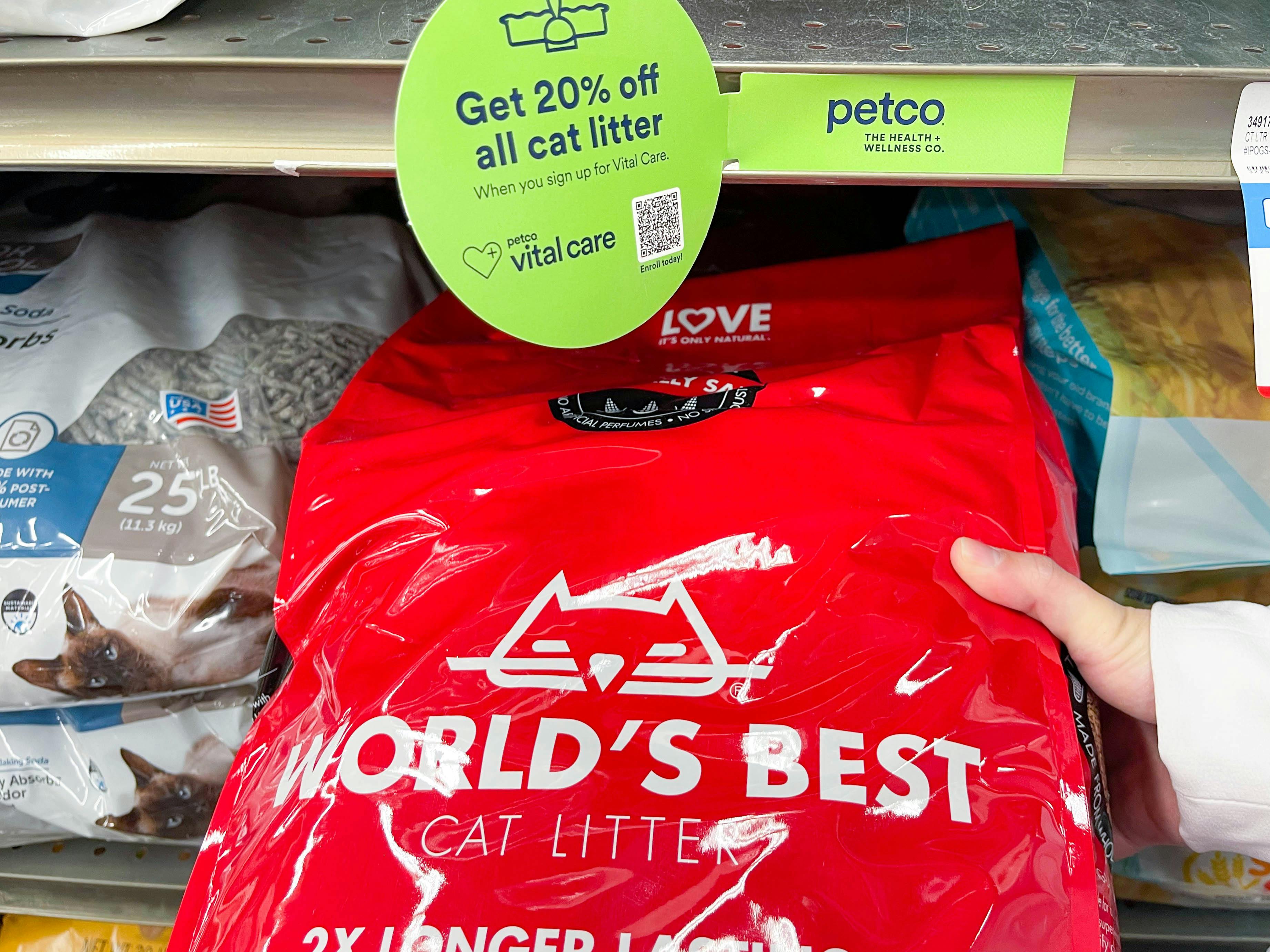 a person holding a bag of worlds best cat litter on the store shelf at petco with vital care signage