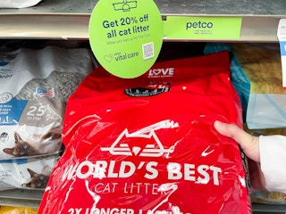 a person holding a bag of worlds best cat litter on the store shelf at petco with vital care signage