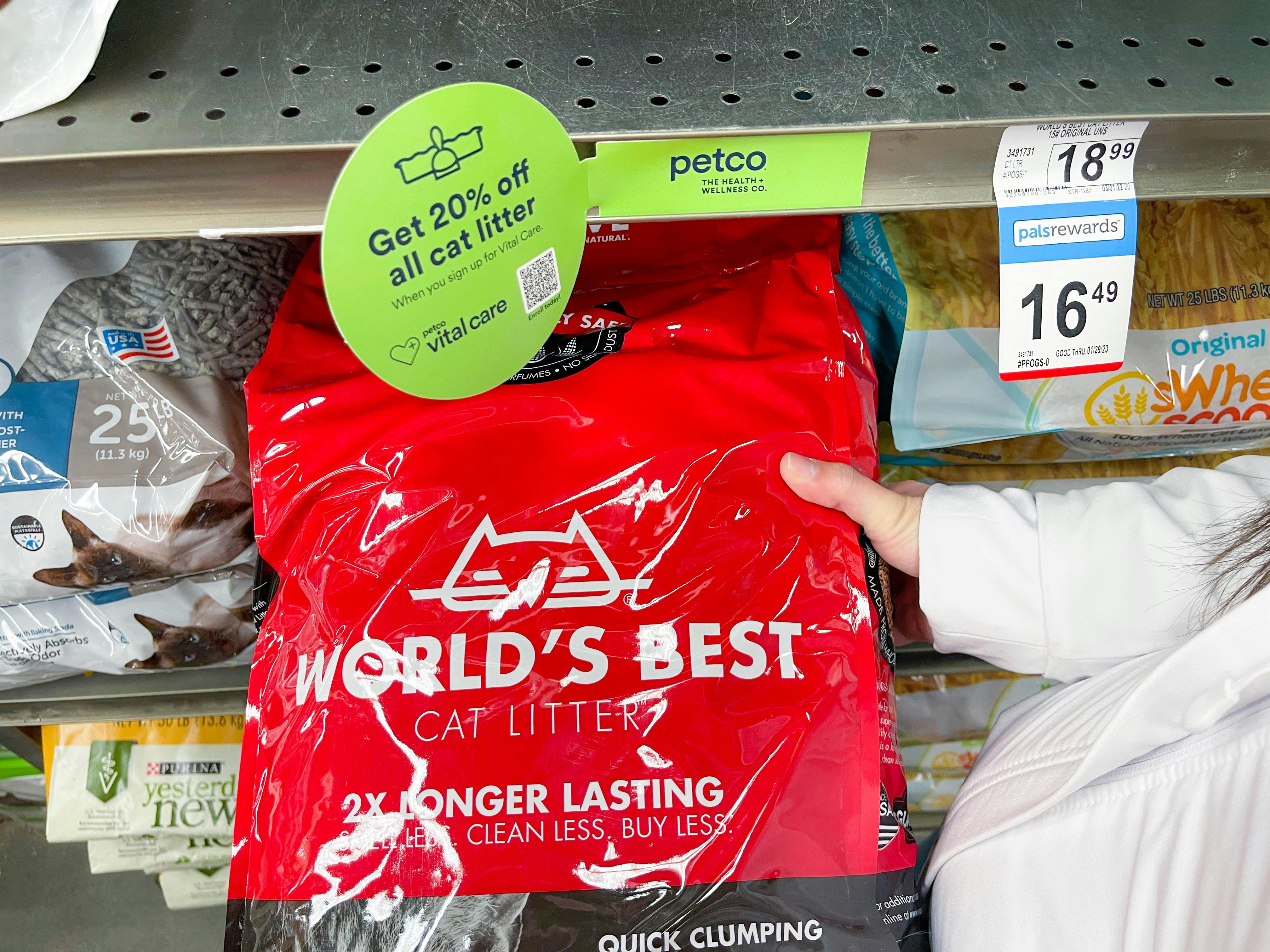 a person holding a bag of worlds best cat litter on the store shelf at petco with vital care signage