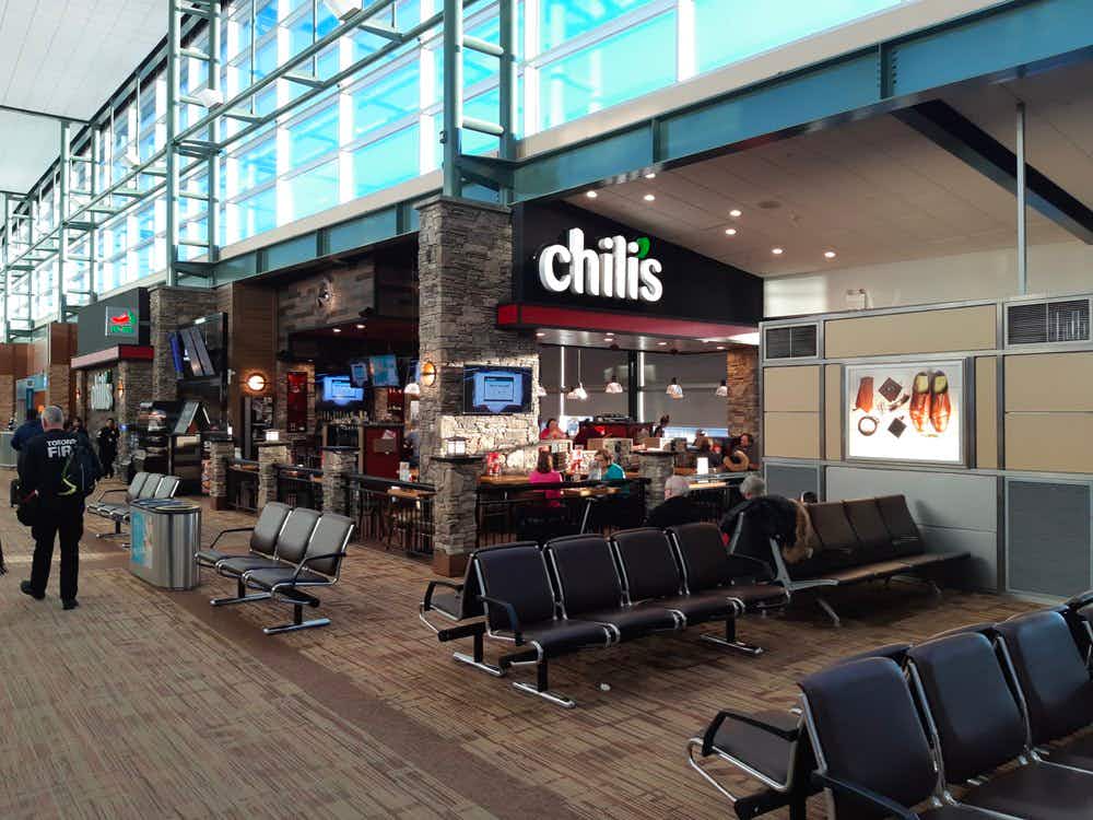 A Chili's inside an airport near some airport seating.