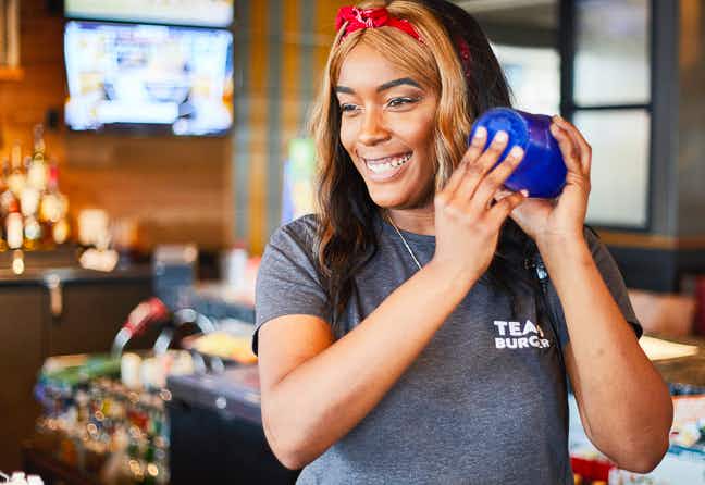 A Chili's employee smiling and shaking up a drink.
