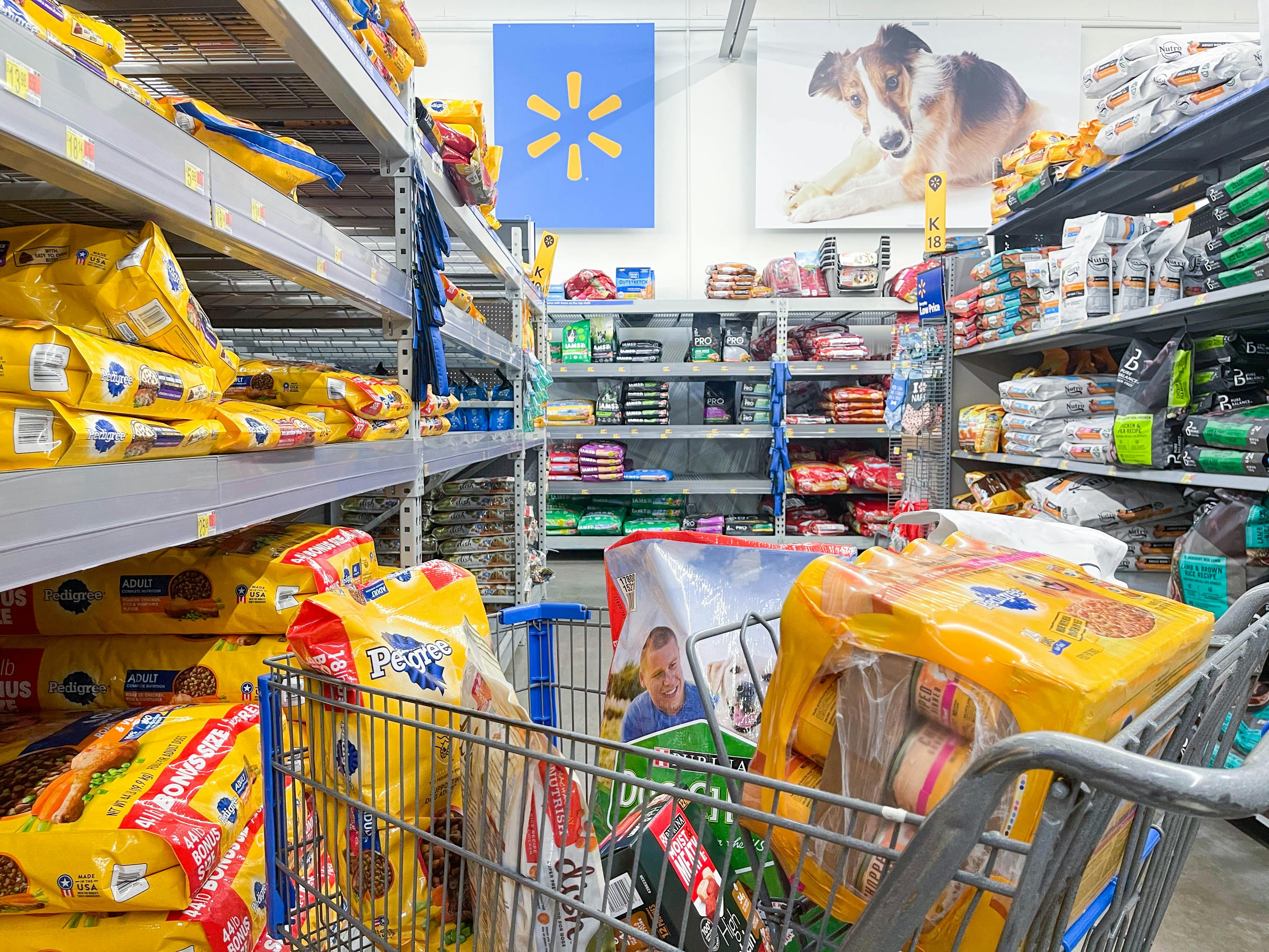 a person pushing a cart filled with dog food in walmart pet section