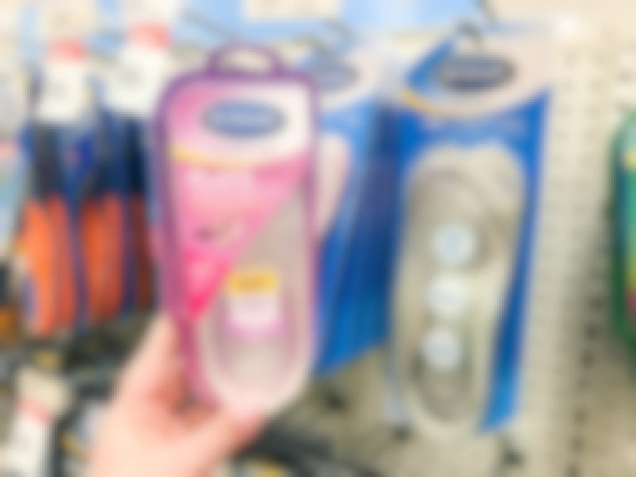 A person's hand grabbing Dr. Scholl's insoles off the display rack. 