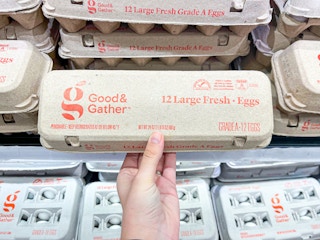 A person holding a carton of a dozen eggs.