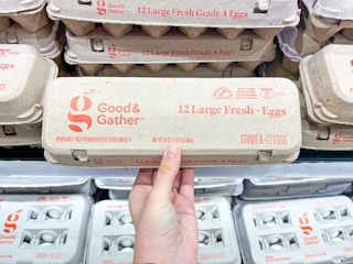 A person holding a carton of a dozen eggs.