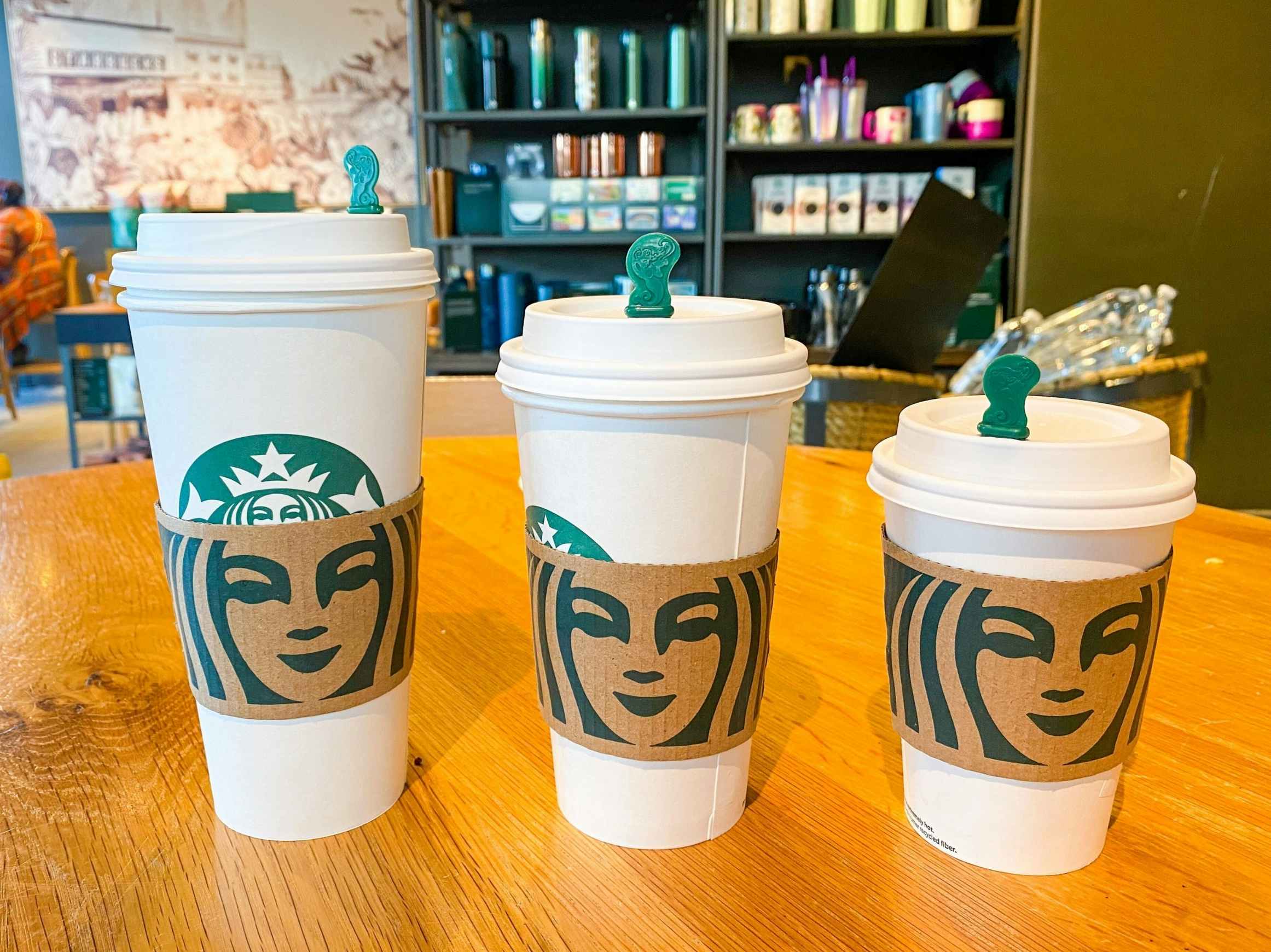 Three hot Starbucks drinks sitting on a table inside Starbucks.