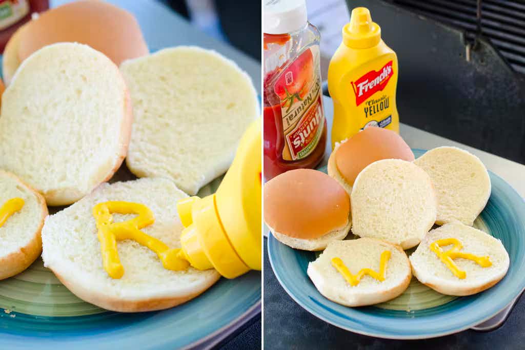 Someone using a mustard bottle to write the letters "W" and "R" on some hamburger buns, and a plate showing the buns next to a bottle of ketchup and a bottle of mustard.