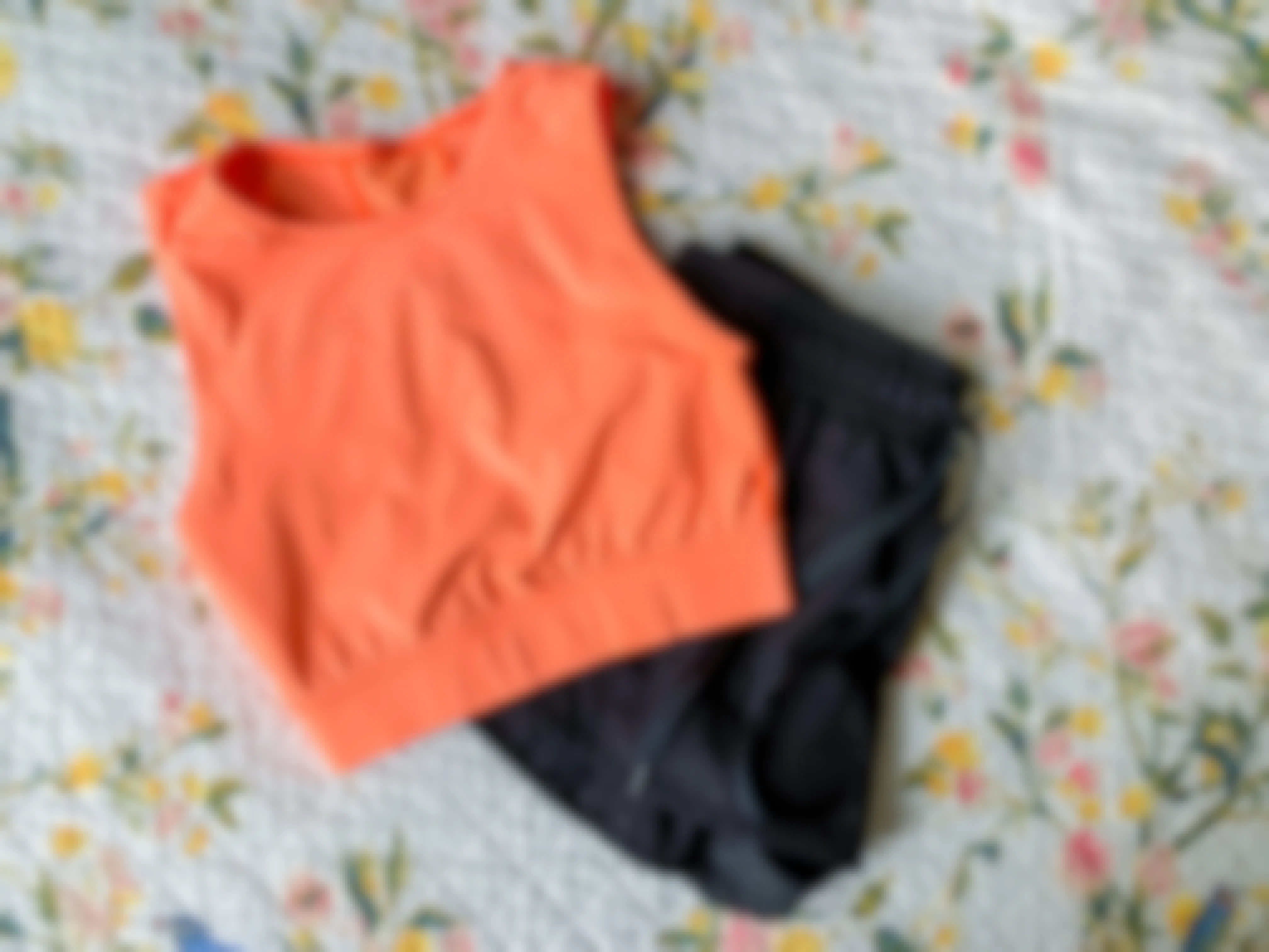 an orange lululemon crop top and a black pair of lulemon athletic shorts laid out on a bedspread