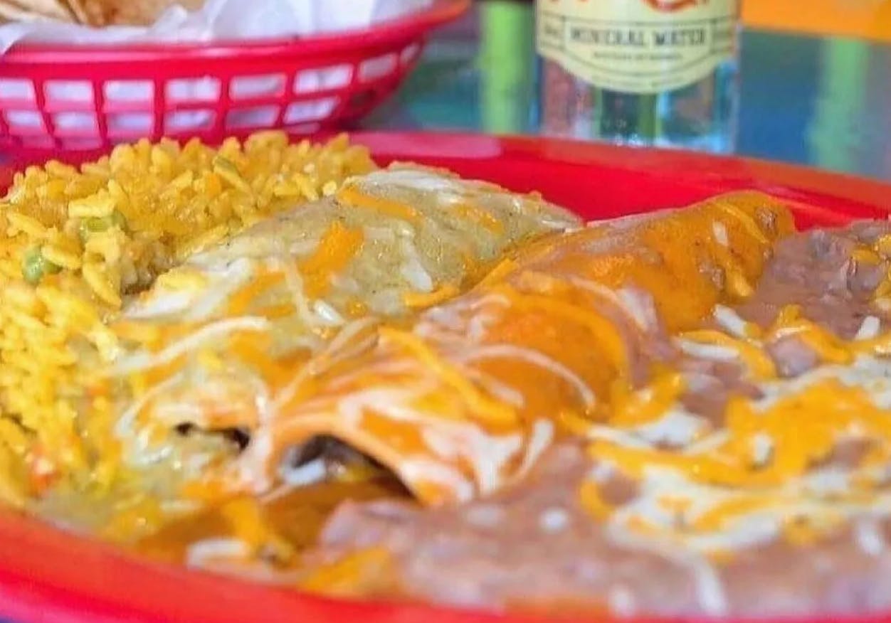 A basket of smothered burritos sitting on a table in Fuzzy's Taco Shop.