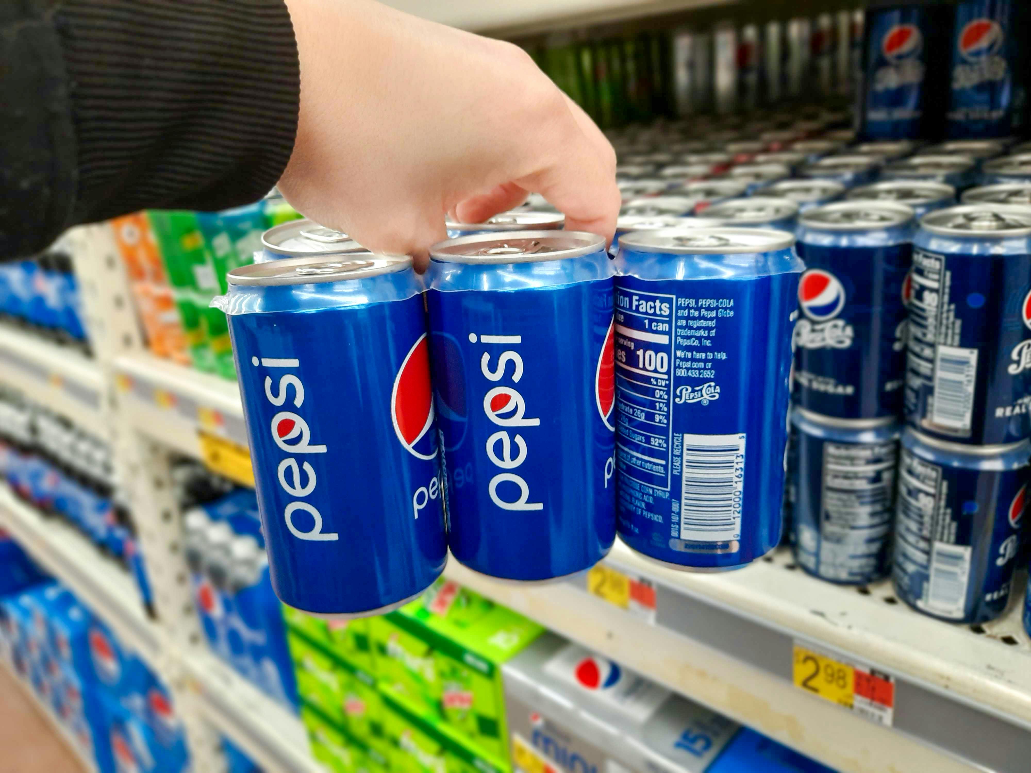 hand holding up mini soda can 6-packs at Walmart